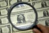 A magnifying glass is held over a 50 subject one dollar note sheet after being printed by an intaglio printing press in Washington, D.C., U.S.