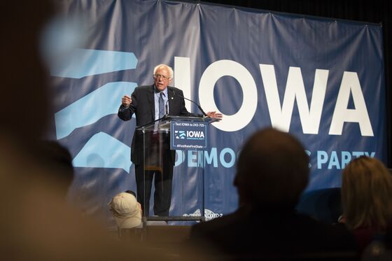 Absent Biden Looms Over Iowa Kickoff Event as Opponents Take Aim