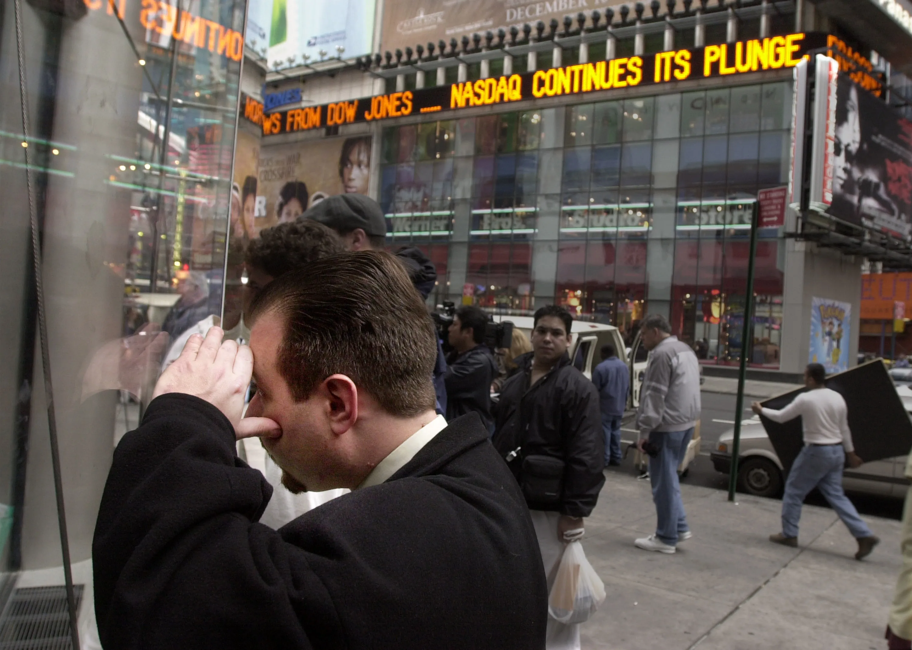 A man who has money in Nasdaq stocks, peers through a window at the Nasdaq board in Times Square in New York City, N.Y., April 4, 2000.&nbsp;
