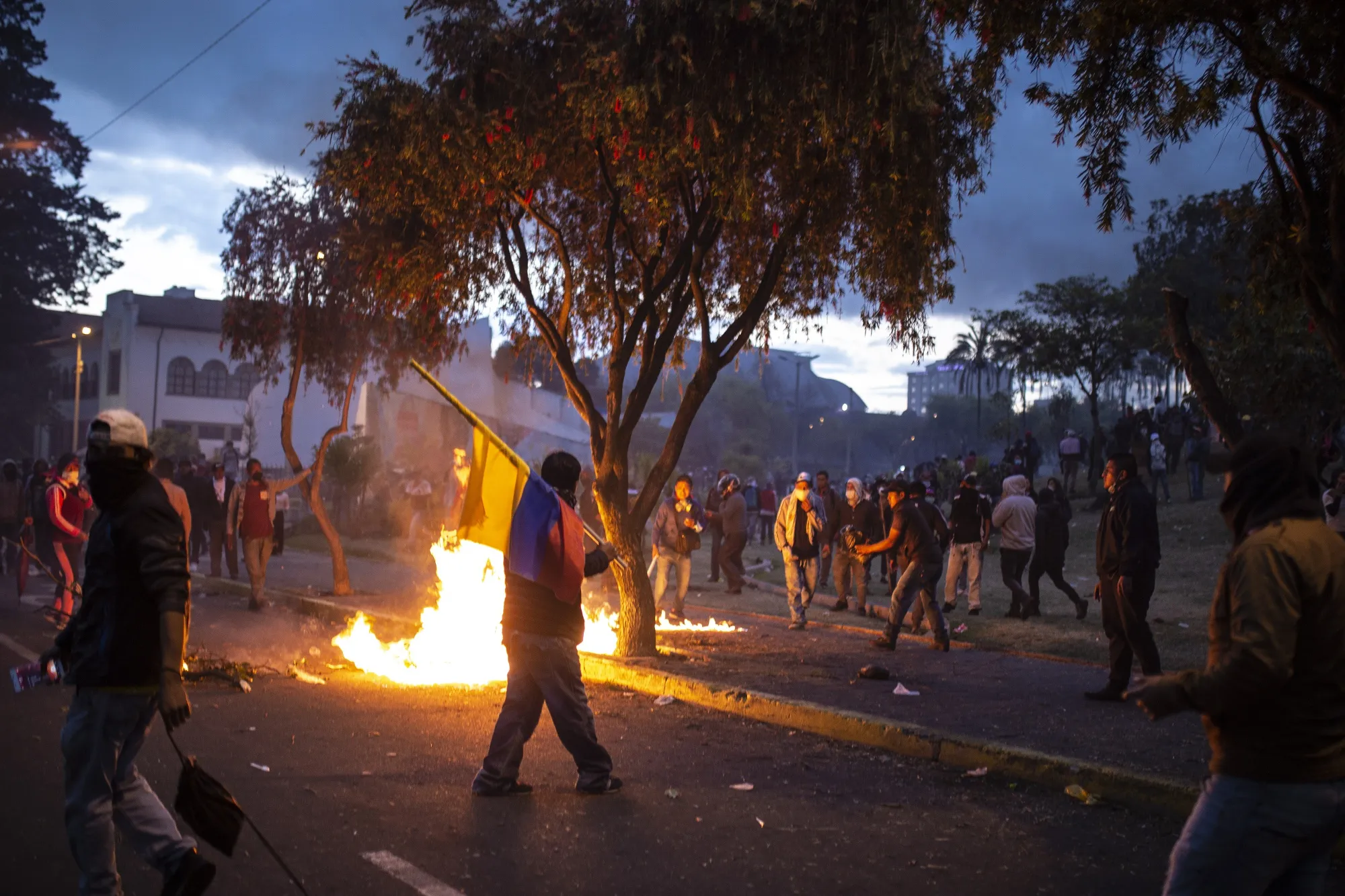 A demonstrator holding an Ecuadorian flag walks past a fire in Quito on Oct. 9.