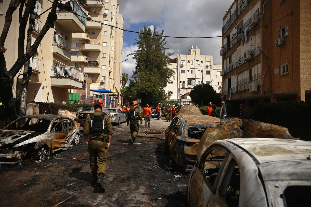 Emergency workers walk through a scorched street after cars and buildings were damaged by a&nbsp;projectile in Petah Tikva, Israel on March 31.
