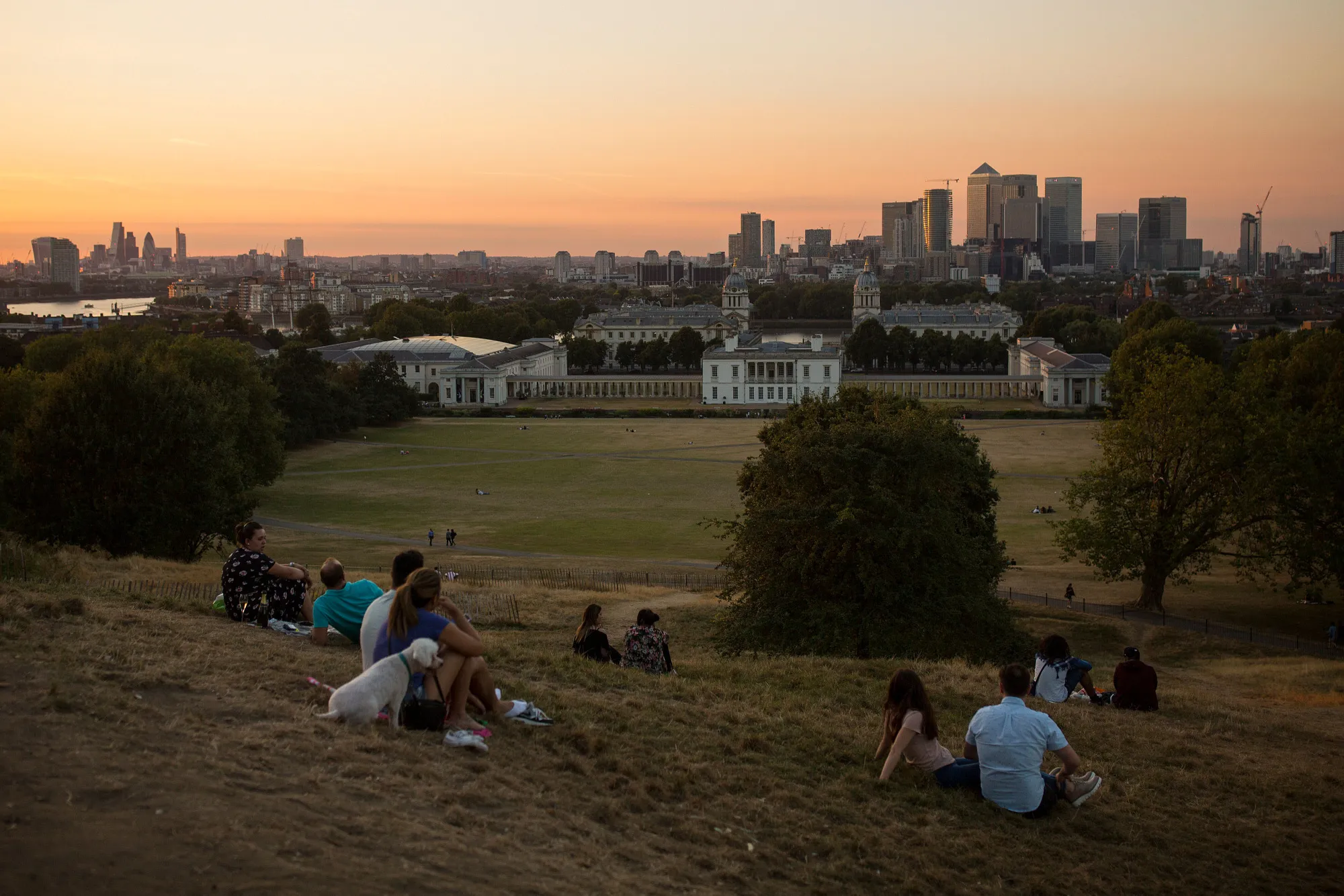 Onlookers sit in Greenwich Park to watch the evening sun set.