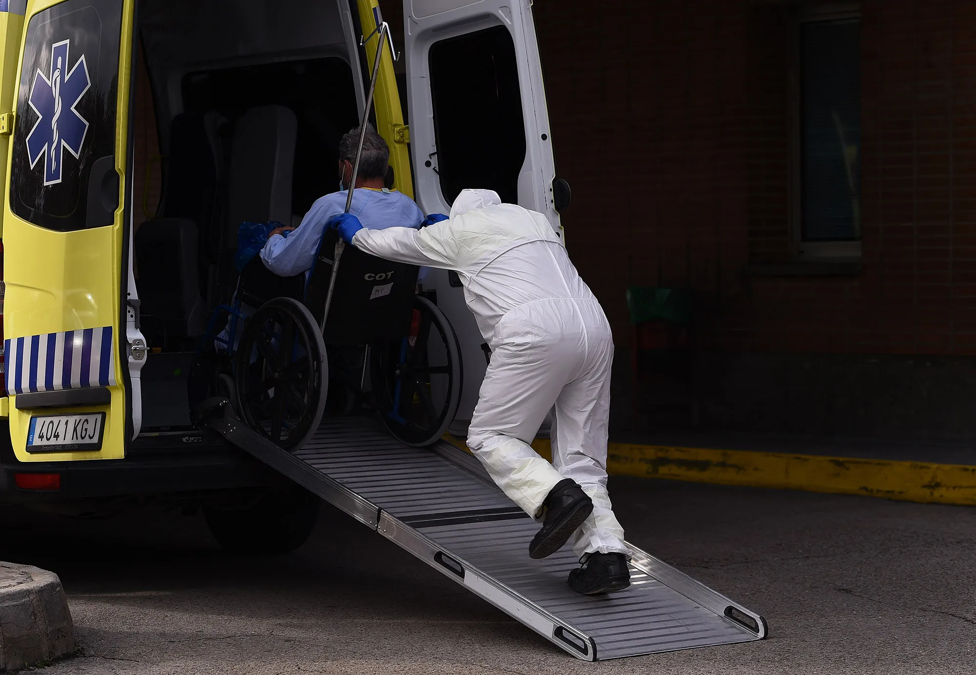 A hospital worker wheels a coronavirus patient into a waiting ambulance to be taken to another sanitary center at the Severo Ochoa hospital in Madrid, on March 27.