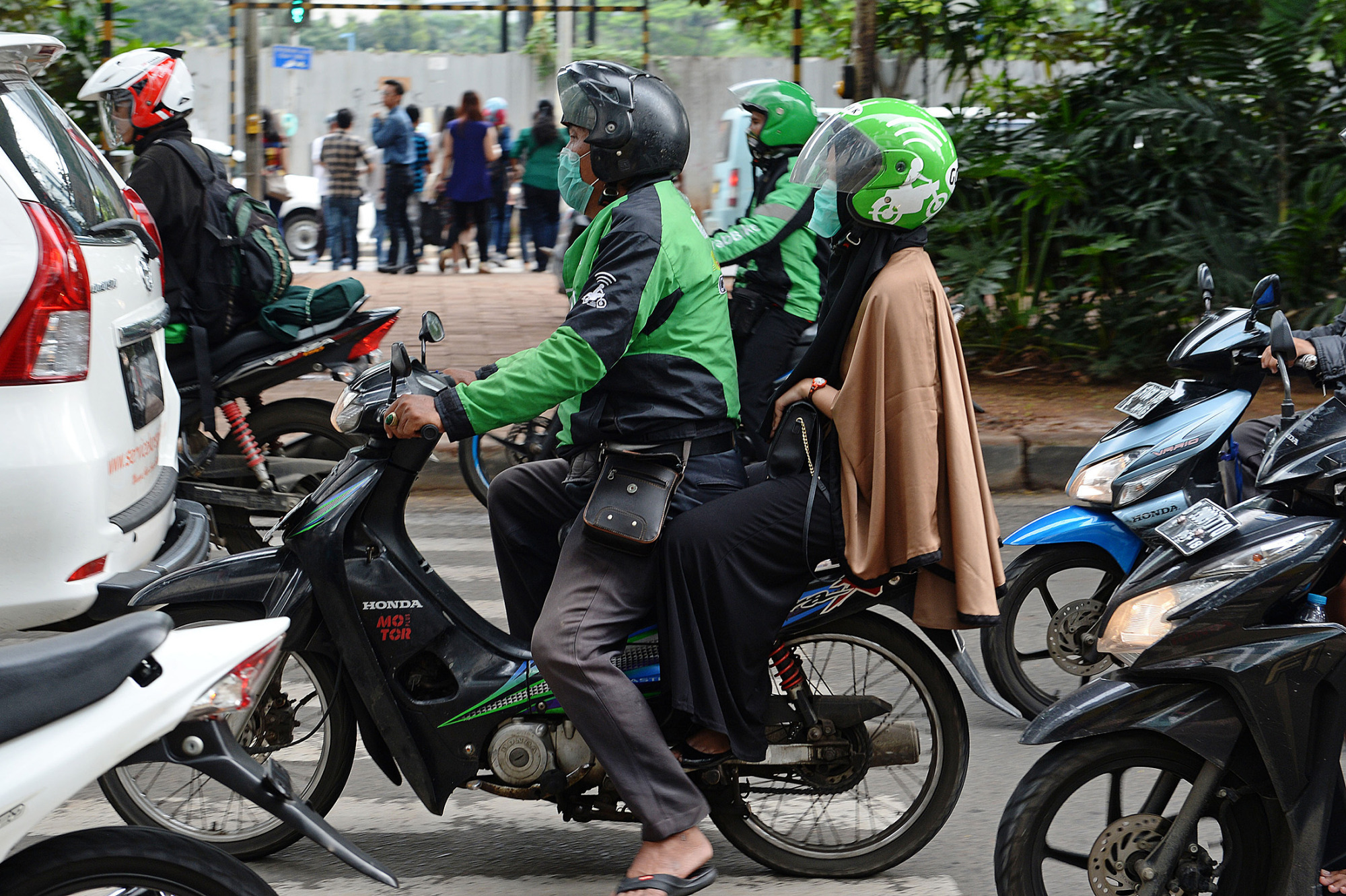 A Go-Jek rider drives a customer through the streets of Jakarta.
