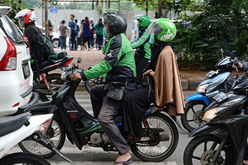 A Go-Jek rider drives a customer through the streets of Jakarta.