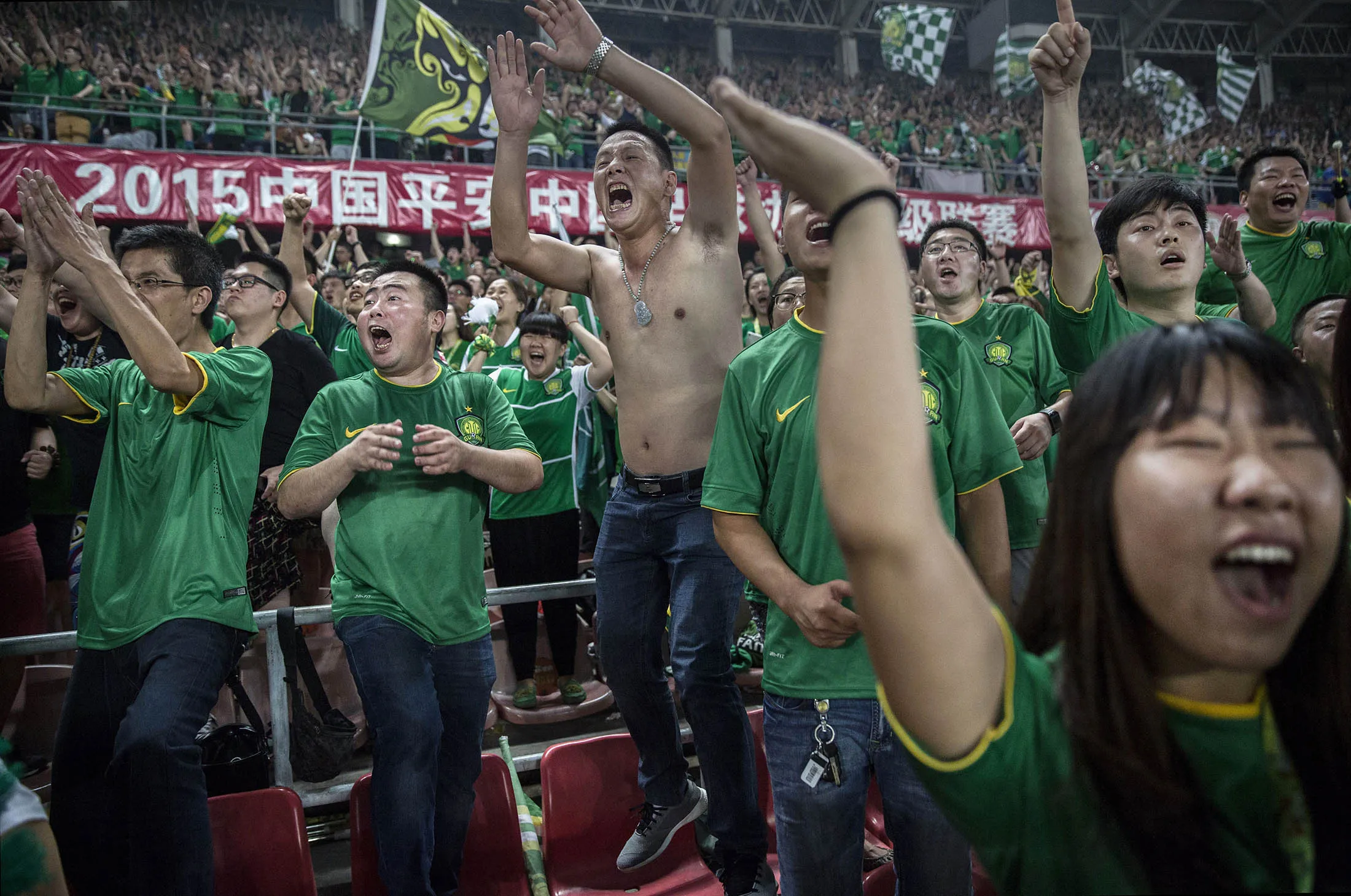 Fans of the Beijing Guoan FC celebrate together after a goal.
