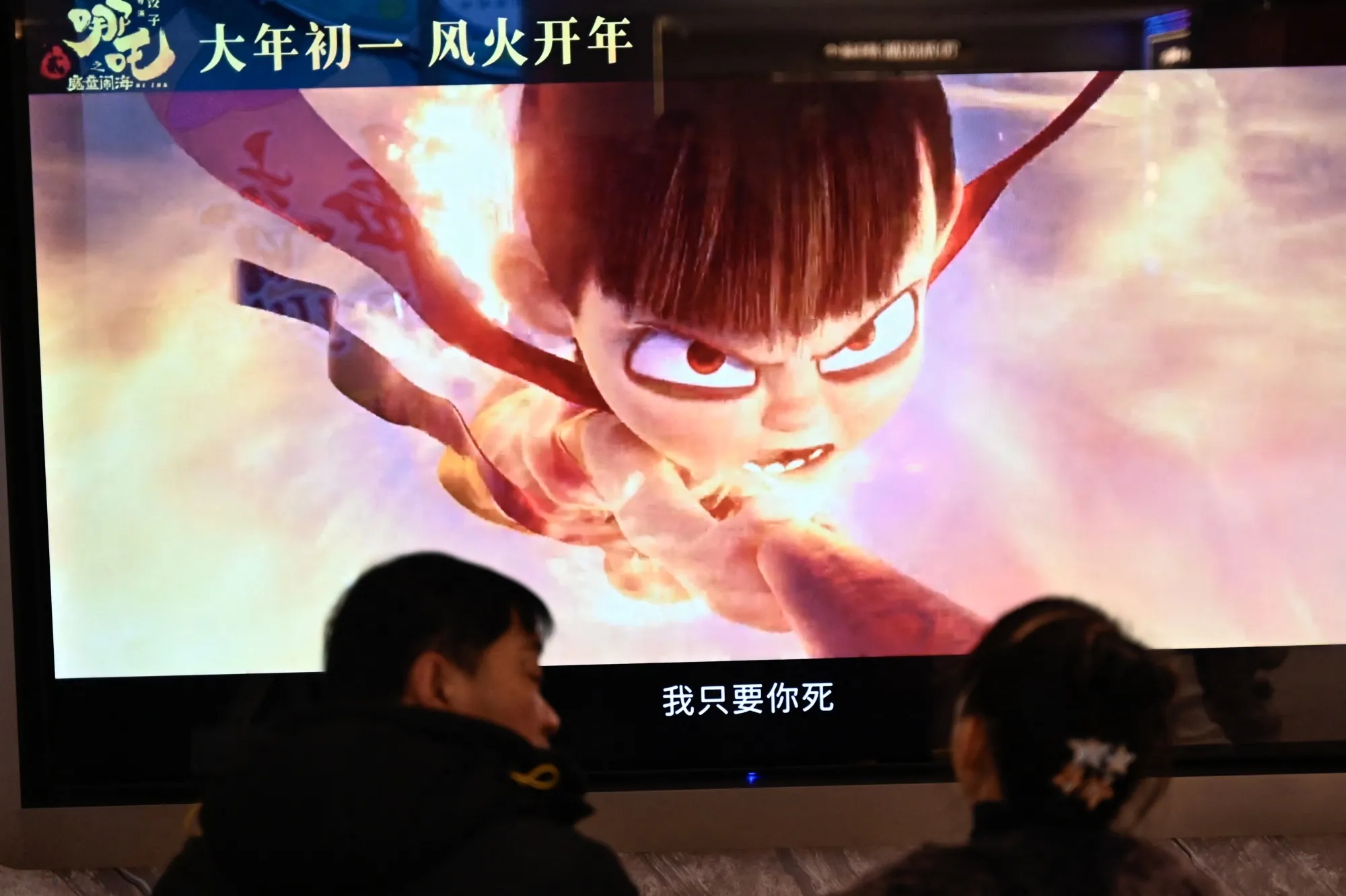 People wait as a screen displays a scene from the Ne Zha 2 animated film at a movie theatre in Beijing on February 16, 2025.&nbsp;