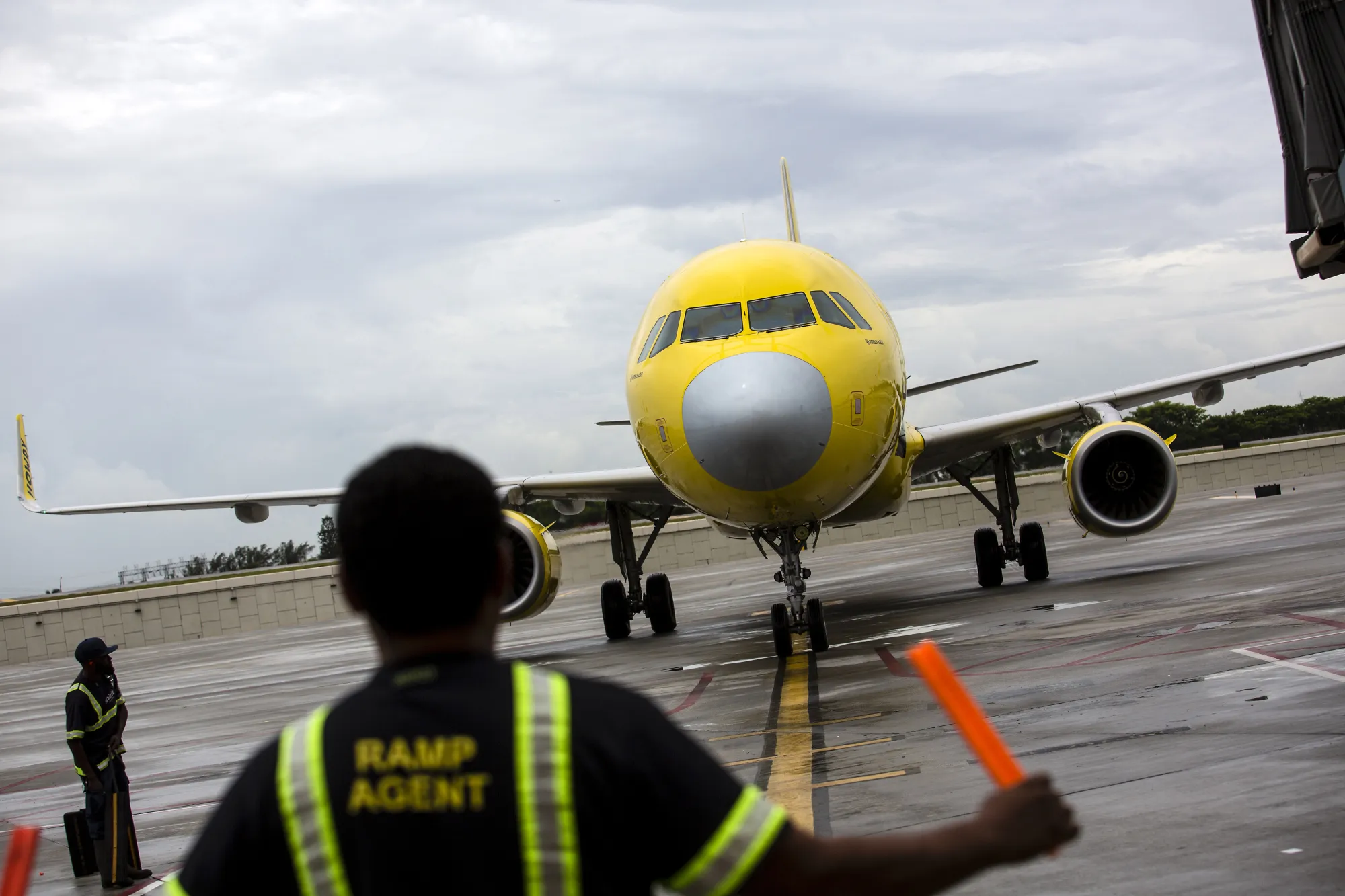An aircraft marshal guides a Spirit Airlines plane&nbsp;at Fort Lauderdale International Airport.&nbsp;