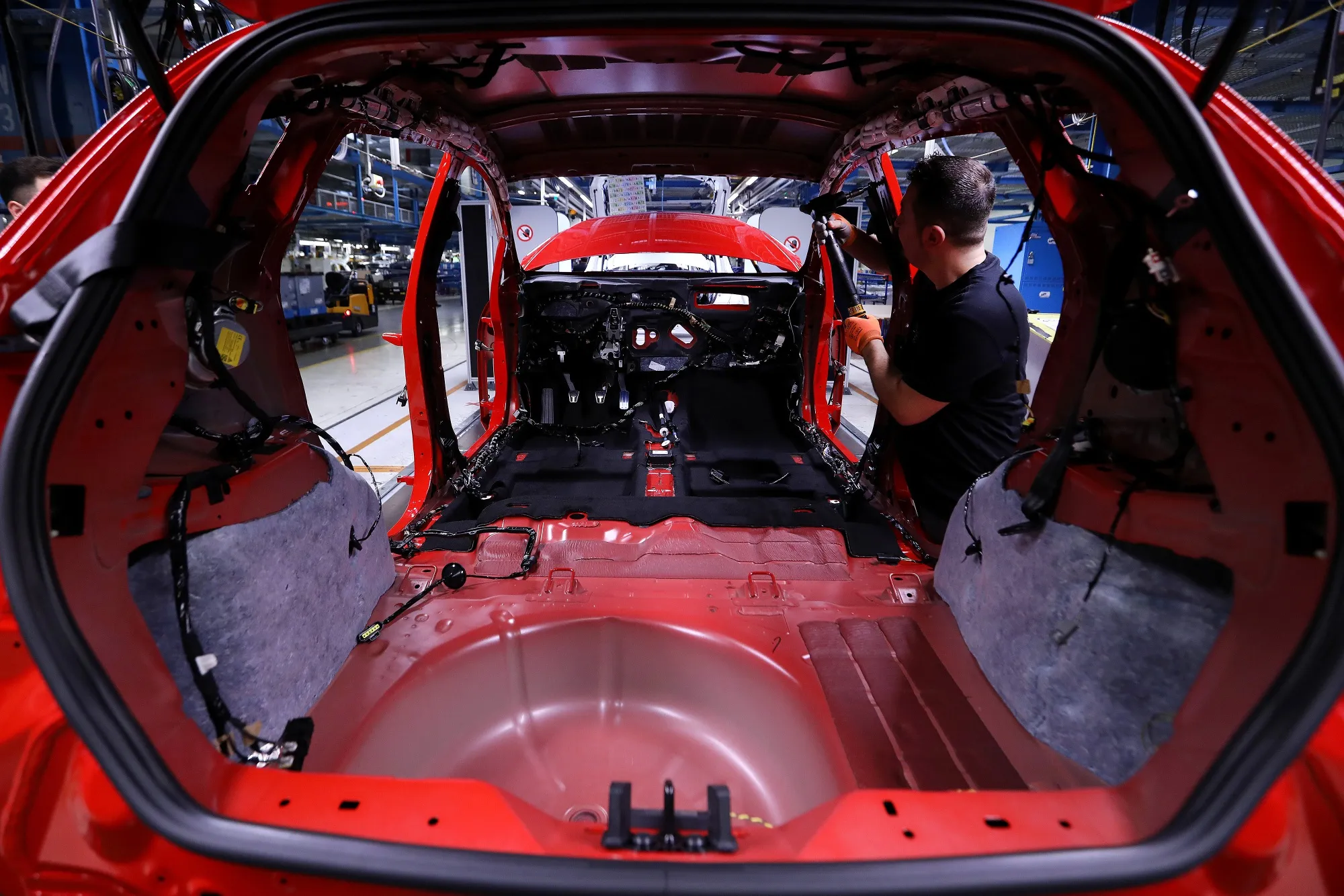 An employee secures seat belt fittings inside an&nbsp;automobile on the assembly line at a factory in Cologne.