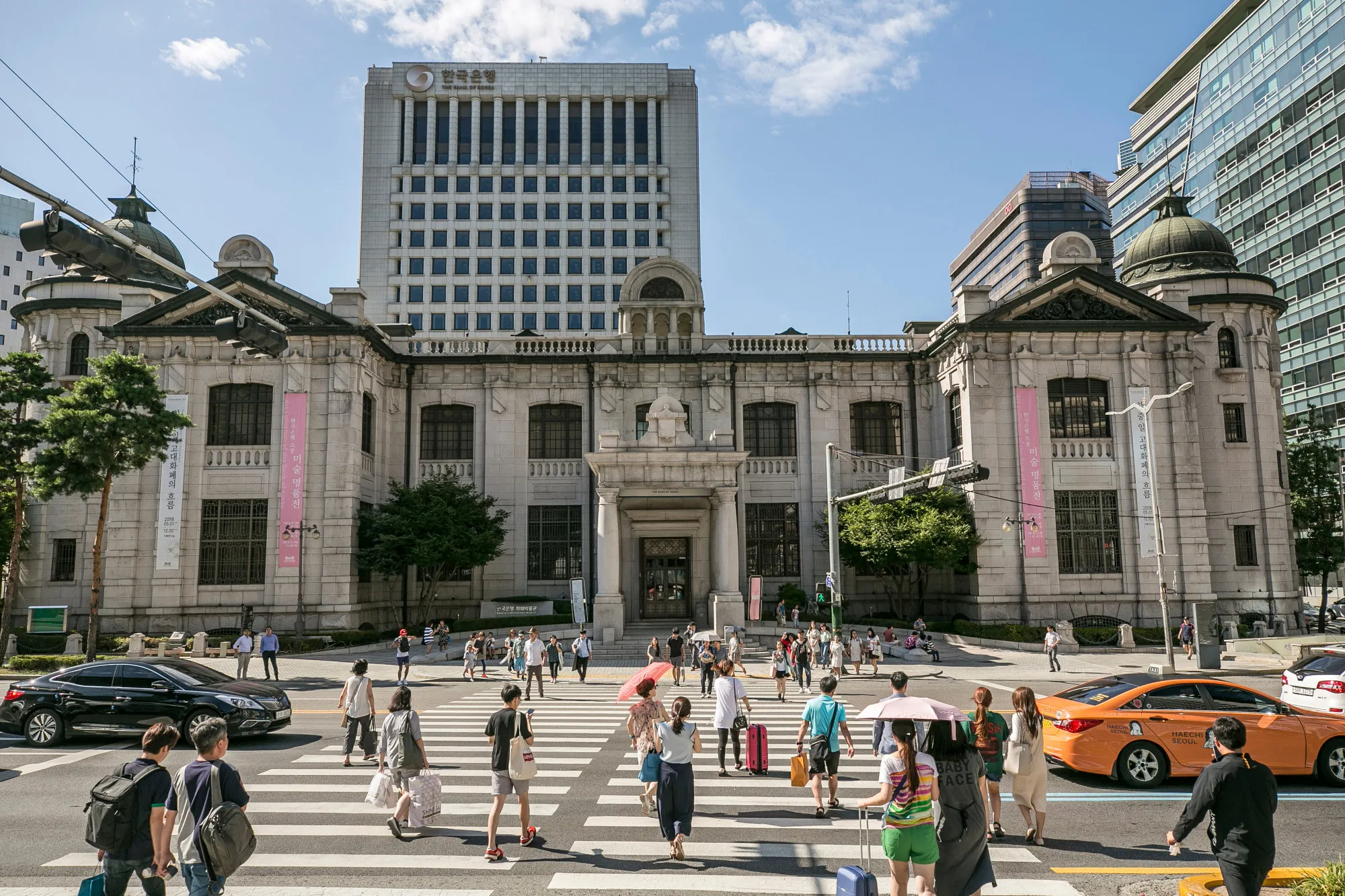 Pedestrians cross a road outside the entrance to the Bank of Korea (BOK) museum at the central bank's headquarters in Seoul, South Korea.