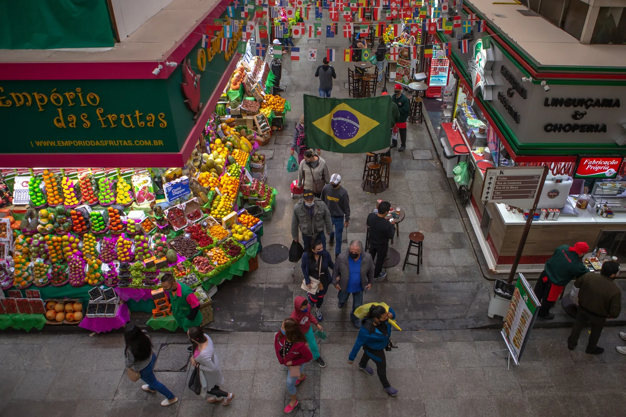 People wearing protective masks walk through a market in Sao Paulo