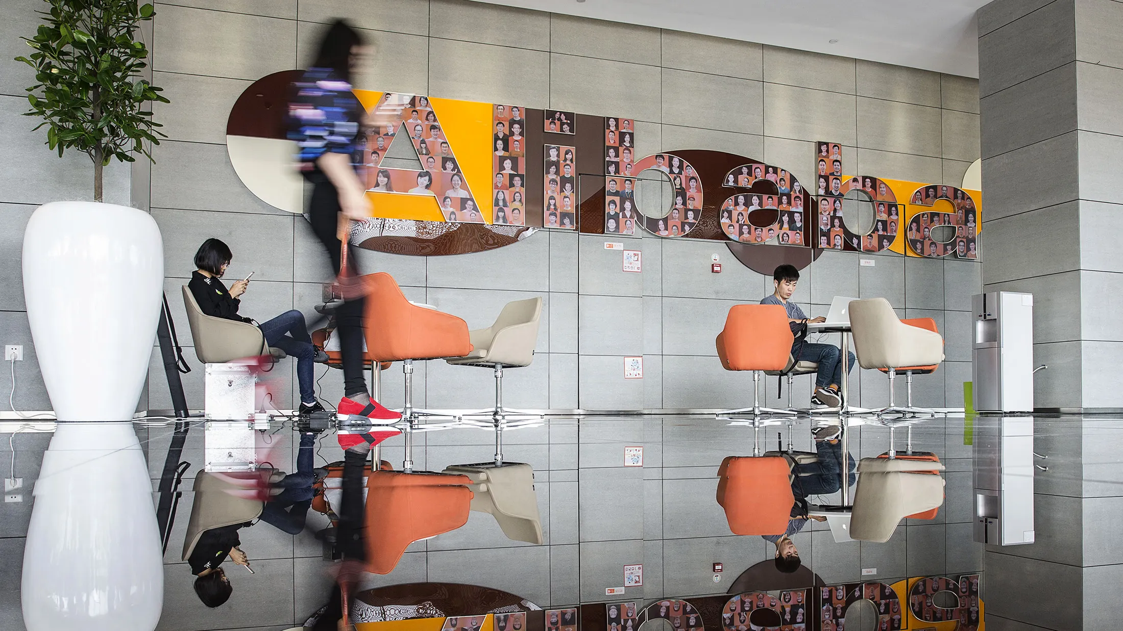 Employees and visitors sit in a lobby at the Alibaba headquarters in Hangzhou, China.
