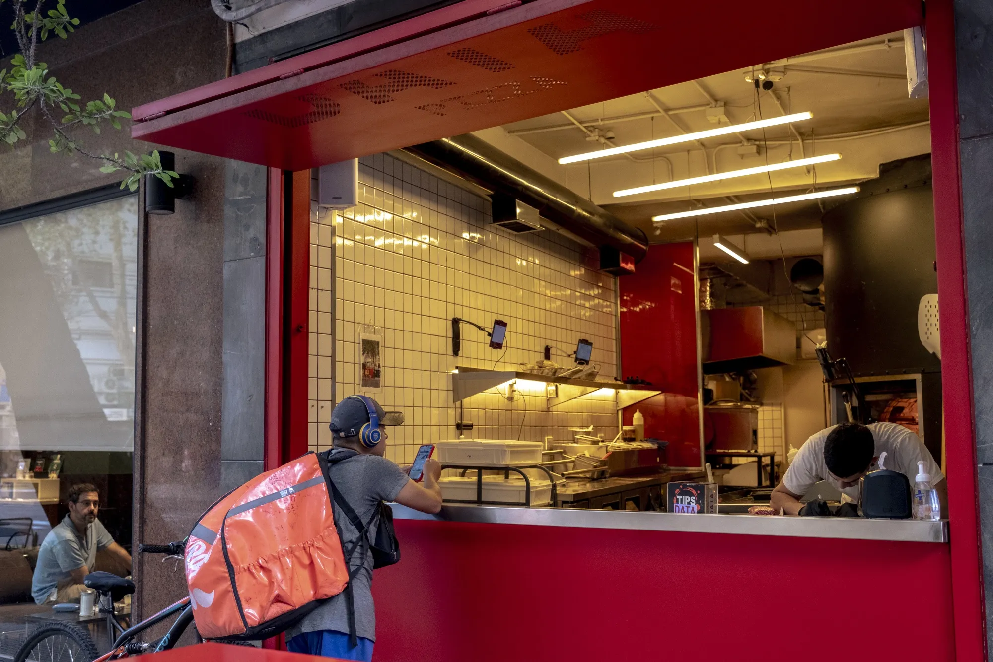 A delivery worker waits for an order outside a restaurant in Buenos Aires.