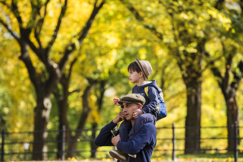 A man carries a boy on his shoulders while walking through Central Park in New York City.