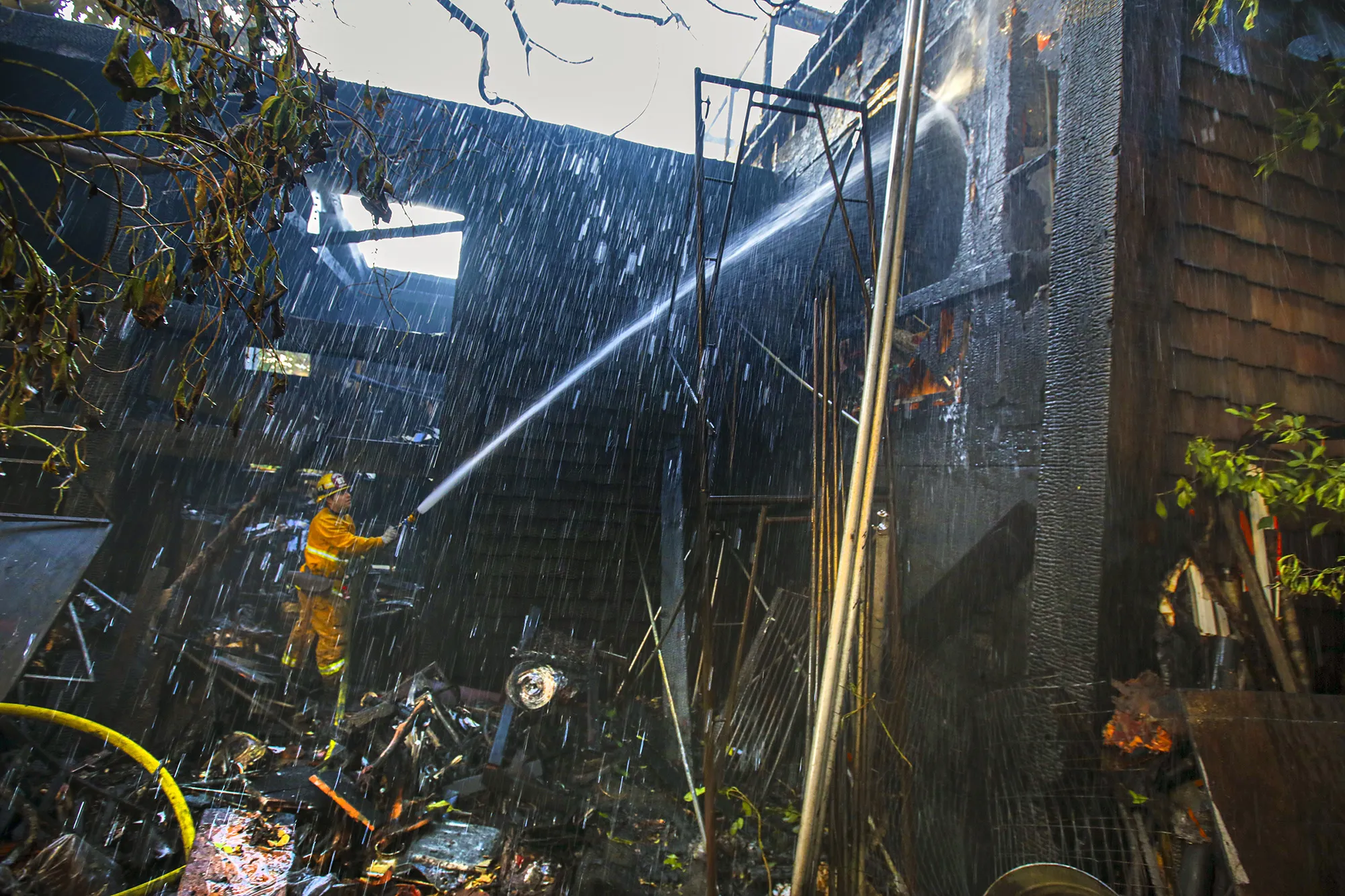 A Los Angeles&nbsp;firefighter douses a smoldering structure with water in Hollywood Hills on Jan. 8.