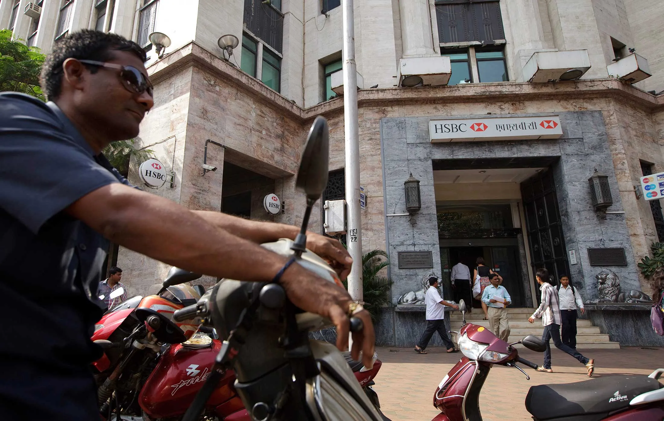 Pedestrians walk by HSBC Bank in Mumbai.
