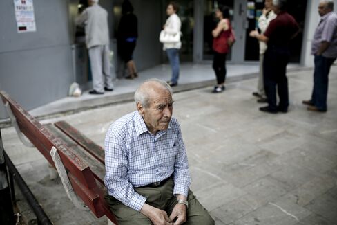 A pensioner sits on a bench beside customers waiting to use an automated teller machine (ATM), outside a National Bank of Greece SA bank branch in Thessaloniki, Greece, on Saturday, June 27, 2015.