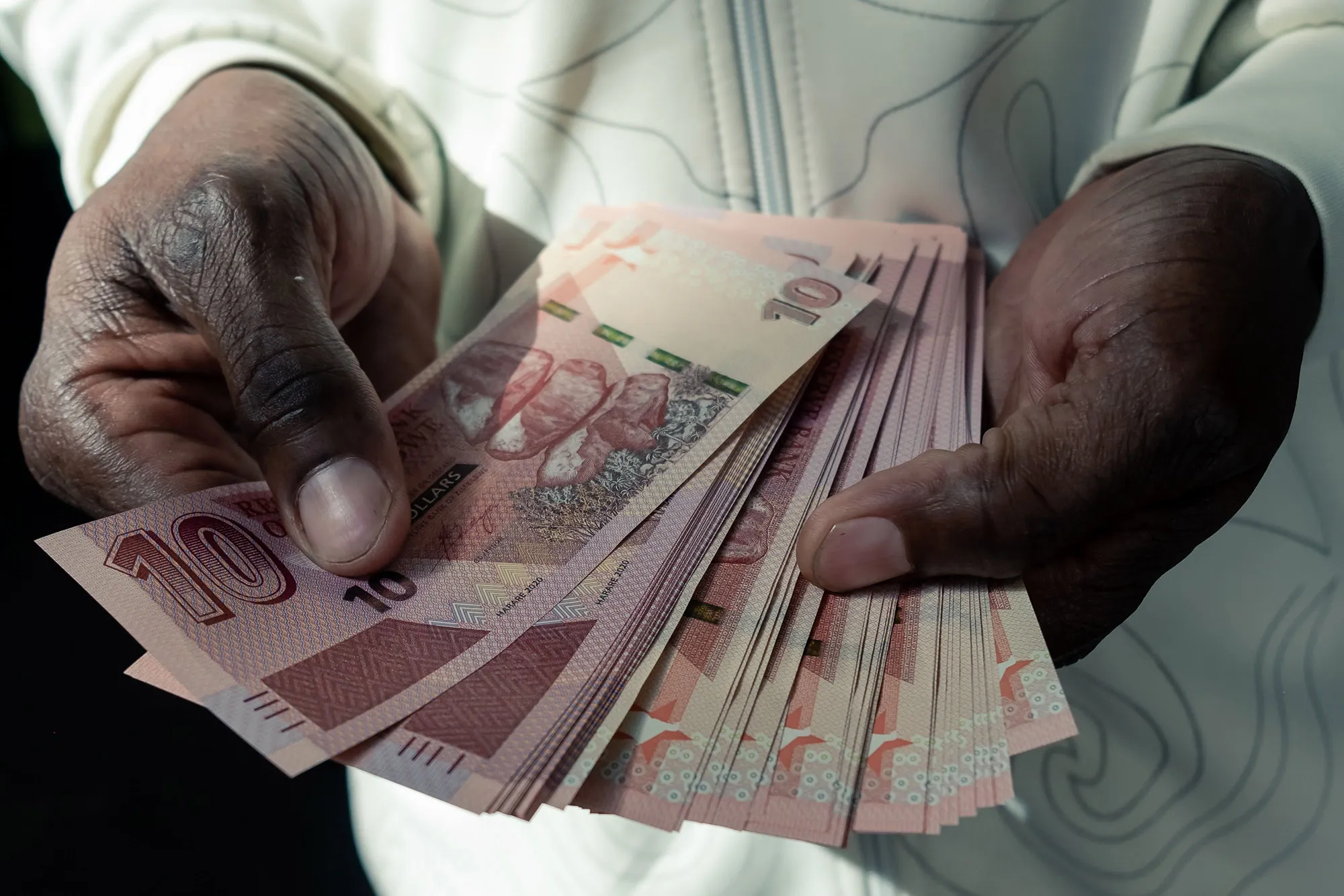 A man counts Zimbabwean ten-dollar notes outside a bank in Harare.