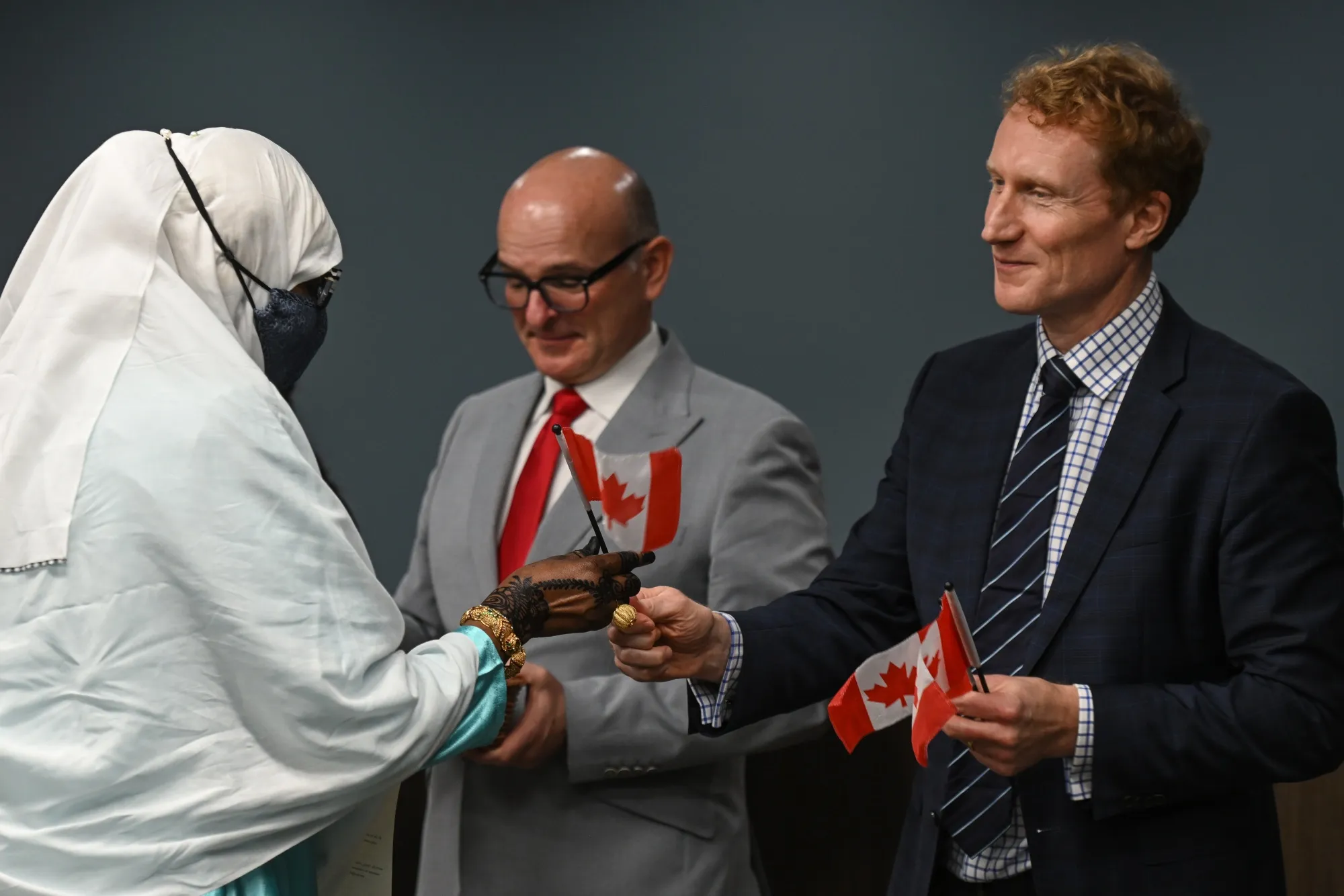 Marc Miller hands a small Canadian flag to a new Canadian citizen during a ceremony at Canada Place in Edmonton, Alberta on Oct. 12.