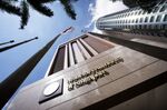 The Singapore national flag flies next to signage for the Monetary Authority of Singapore (MAS) displayed outside the central bank's headquarters in Singapore.