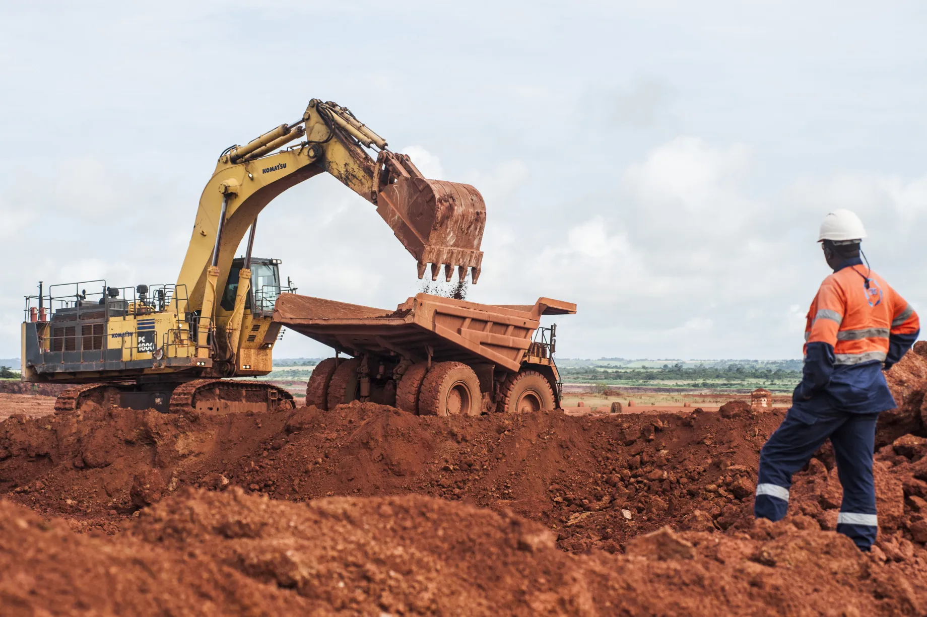 A worker watches as a digger unloads raw bauxite into a truck at a&nbsp;mine&nbsp;near Boke, Guinea.