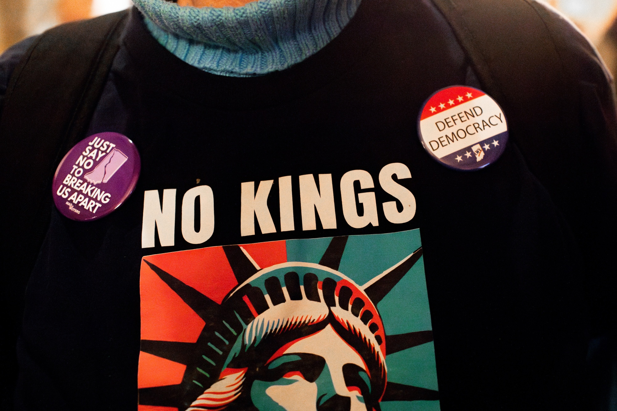 A demonstrator wears a "No Kings" shirt at the Indiana Statehouse in Indianapolis, Indiana, US, on Monday, Dec. 8, 2025. An explosion of fiercely partisan mid-decade redistricting contests has been a top priority for President Donald Trump, who has an eye on the razor-thin GOP House majority offering a bulwark between himself and a hostile legislative branch that can gum up his agenda. Photographer: Kaiti Sullivan/Bloomberg