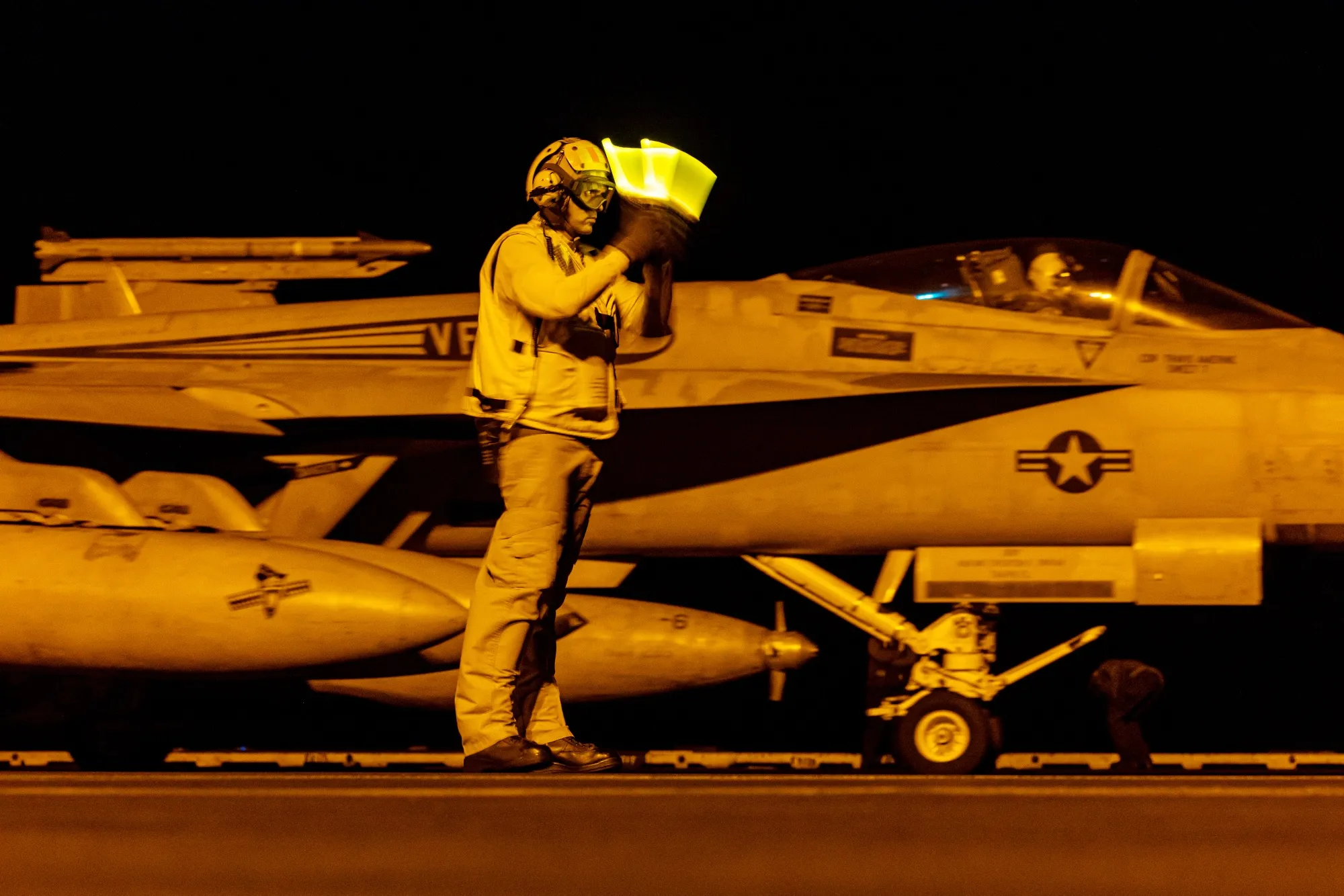 A member of the flight deck crew signaling as an F/A-18 Super Hornet fighter jet takes off from the USS Dwight D. Eisenhower&nbsp;aircraft carrier on operation in the Southern Red Sea, on March 19.