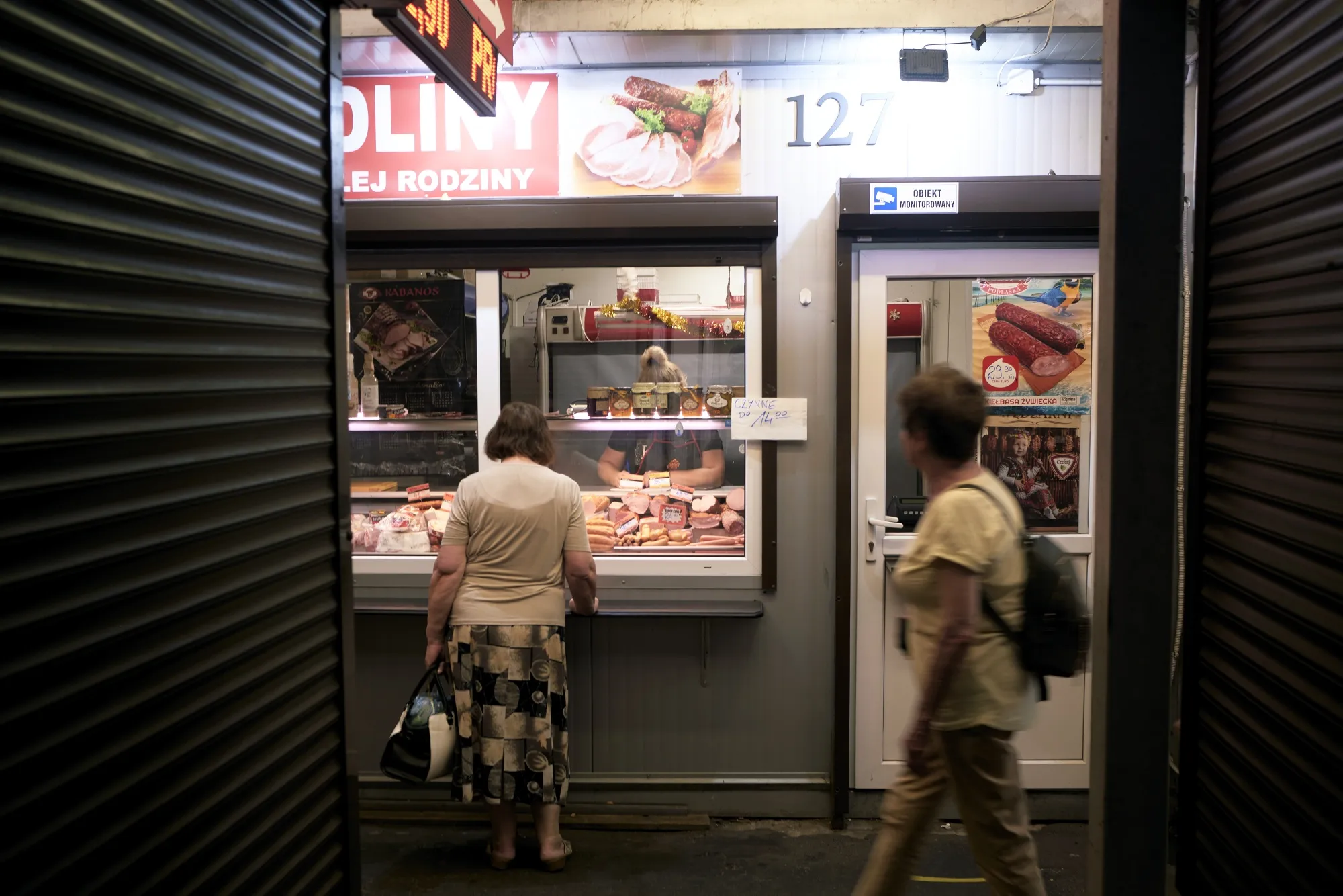 A customer shops at a butcher's stall in a food market in Warsaw.
