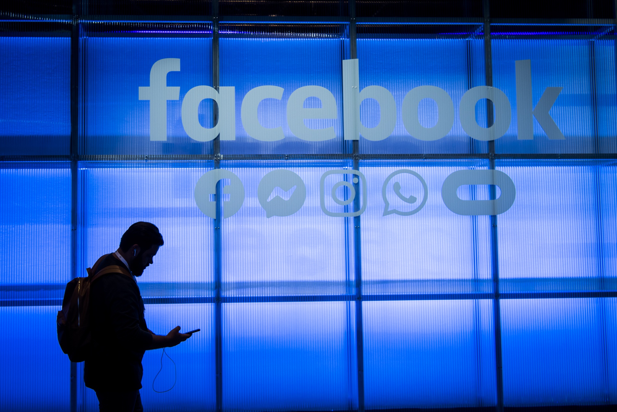 An attendee looks at a mobile phone while walking the demonstration room during the F8 Developers Conference in San Jose, California, U.S., on Tuesday, April 30, 2019. 