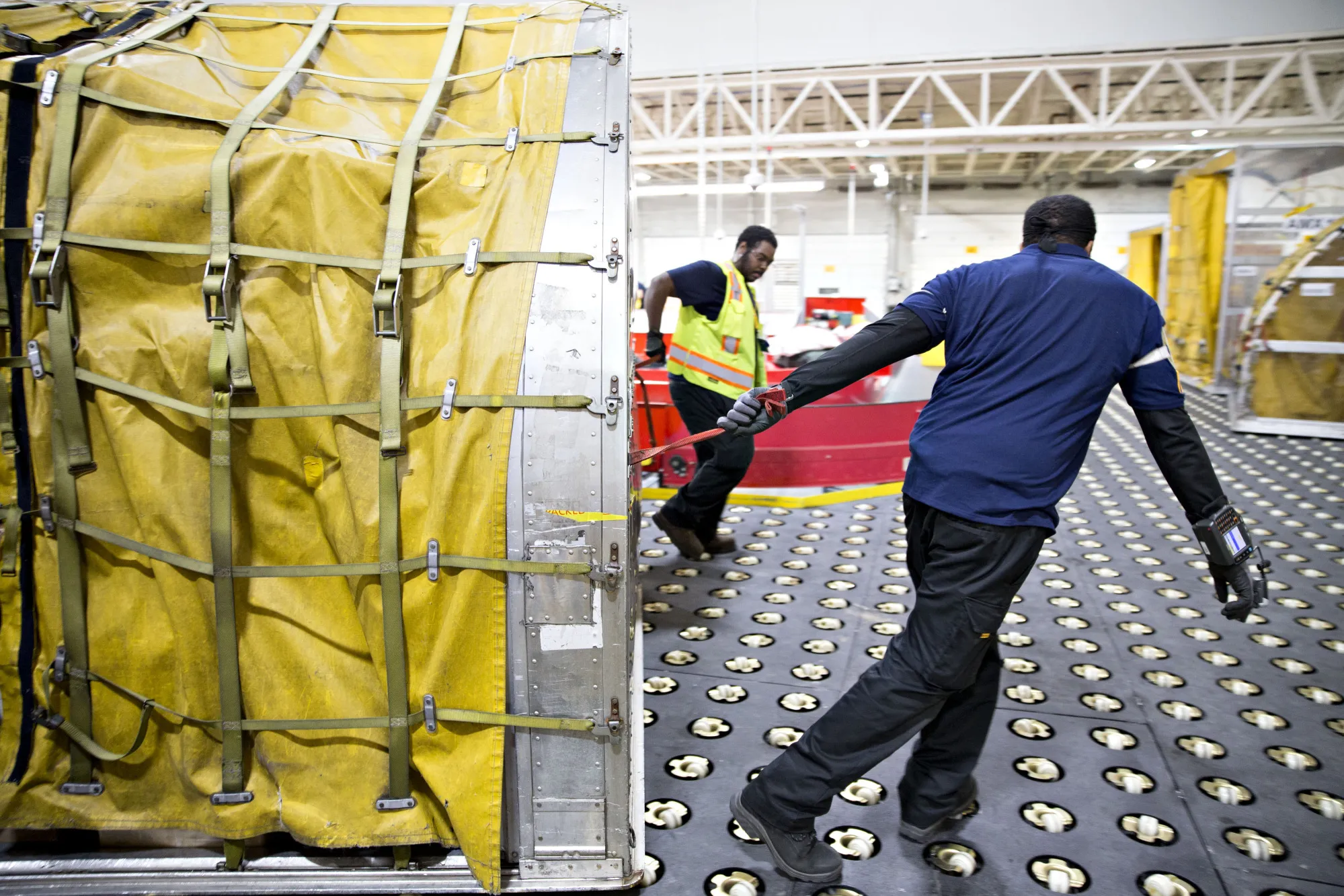 Employees move a container towards a loading bay at a DHL Worldwide Express facility ahead of Cyber Monday in Chicago, Illinois