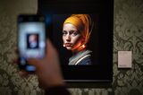 A visitor takes a picture with his mobile phone of an image designed with artificial intelligence by Berlin-based digital creator Julian van Dieken, inspired by Johannes Vermeer's painting "Girl with a Pearl Earring.”