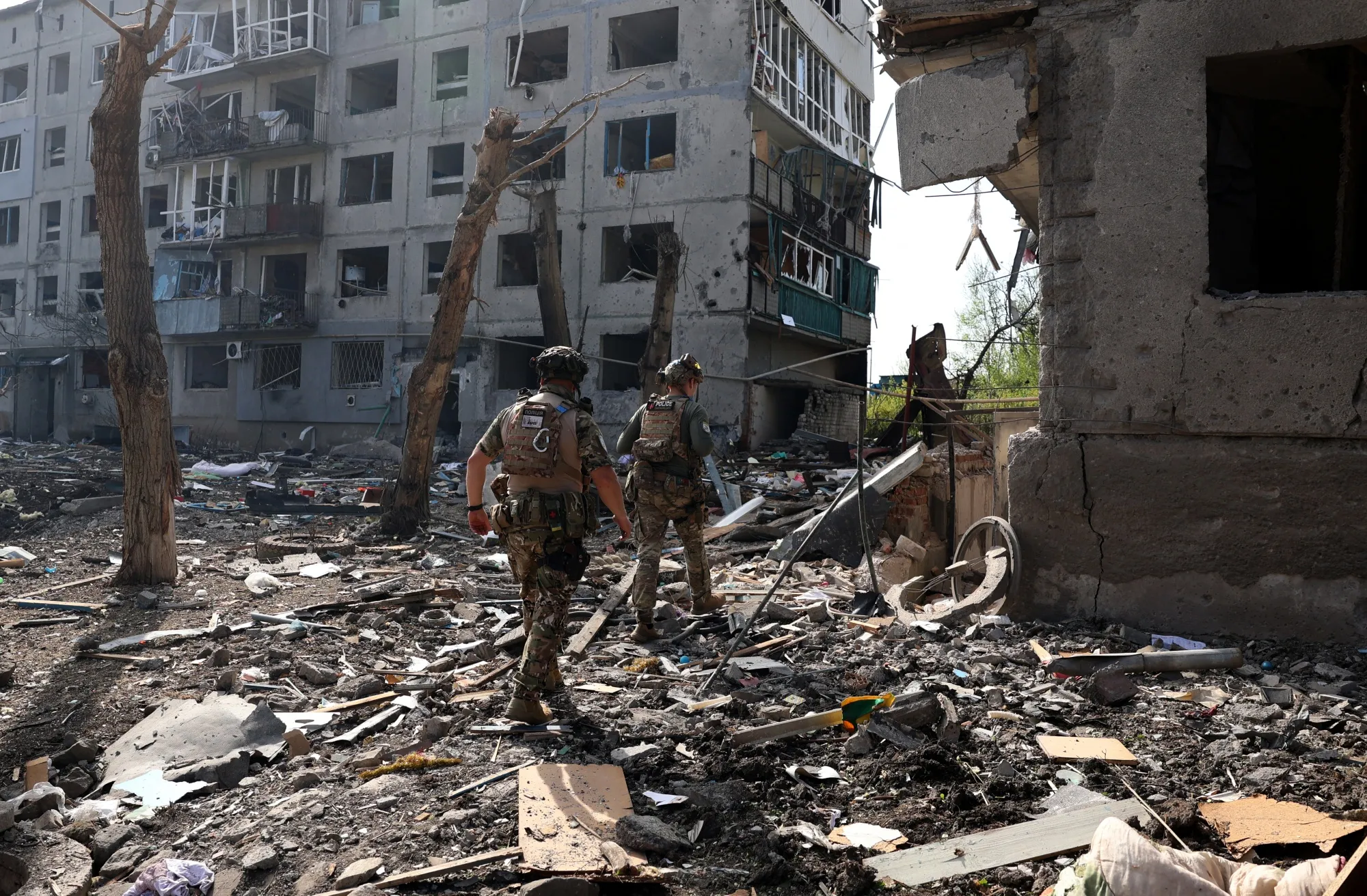 Officers of the special police force "White Angel" Hennadiy Yudin 47(L) and Dmytro Solovyi 23 (R) walk past destroyed buildings and debris during the evacuation of local residents from the village of Ocheretyne not far from Avdiivka town in the Donetsk region, on April 15, 2024, amid the Russian invasion in Ukraine. (Photo by Anatolii STEPANOV / AFP) (Photo by ANATOLII STEPANOV/AFP via Getty Images)
