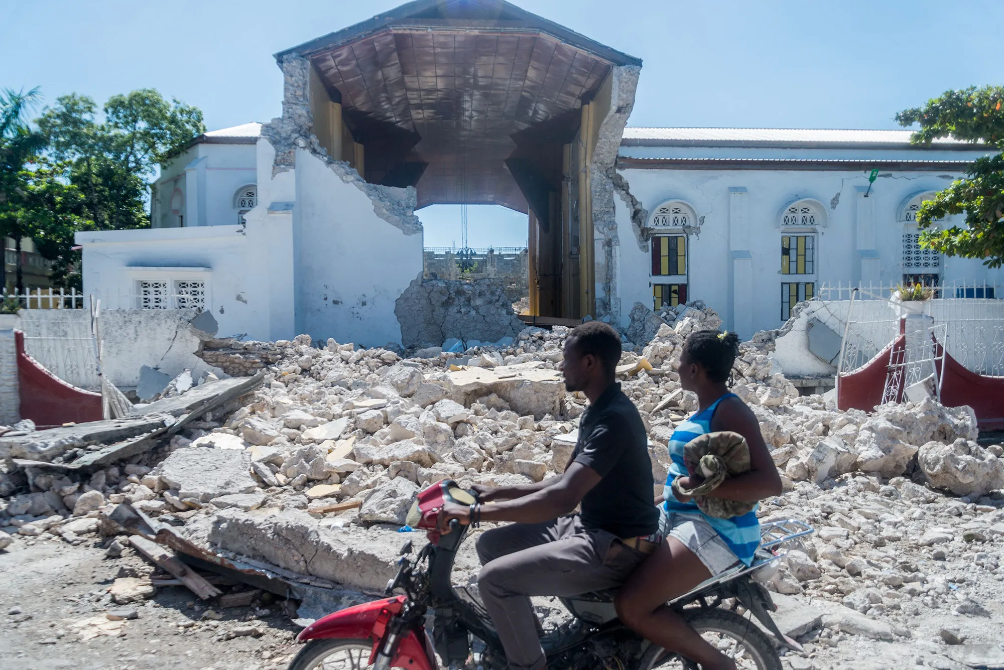 People drive past the remains of the "Sacré coeur des Cayes" church in Les Cayes, Haiti on Aug.15.