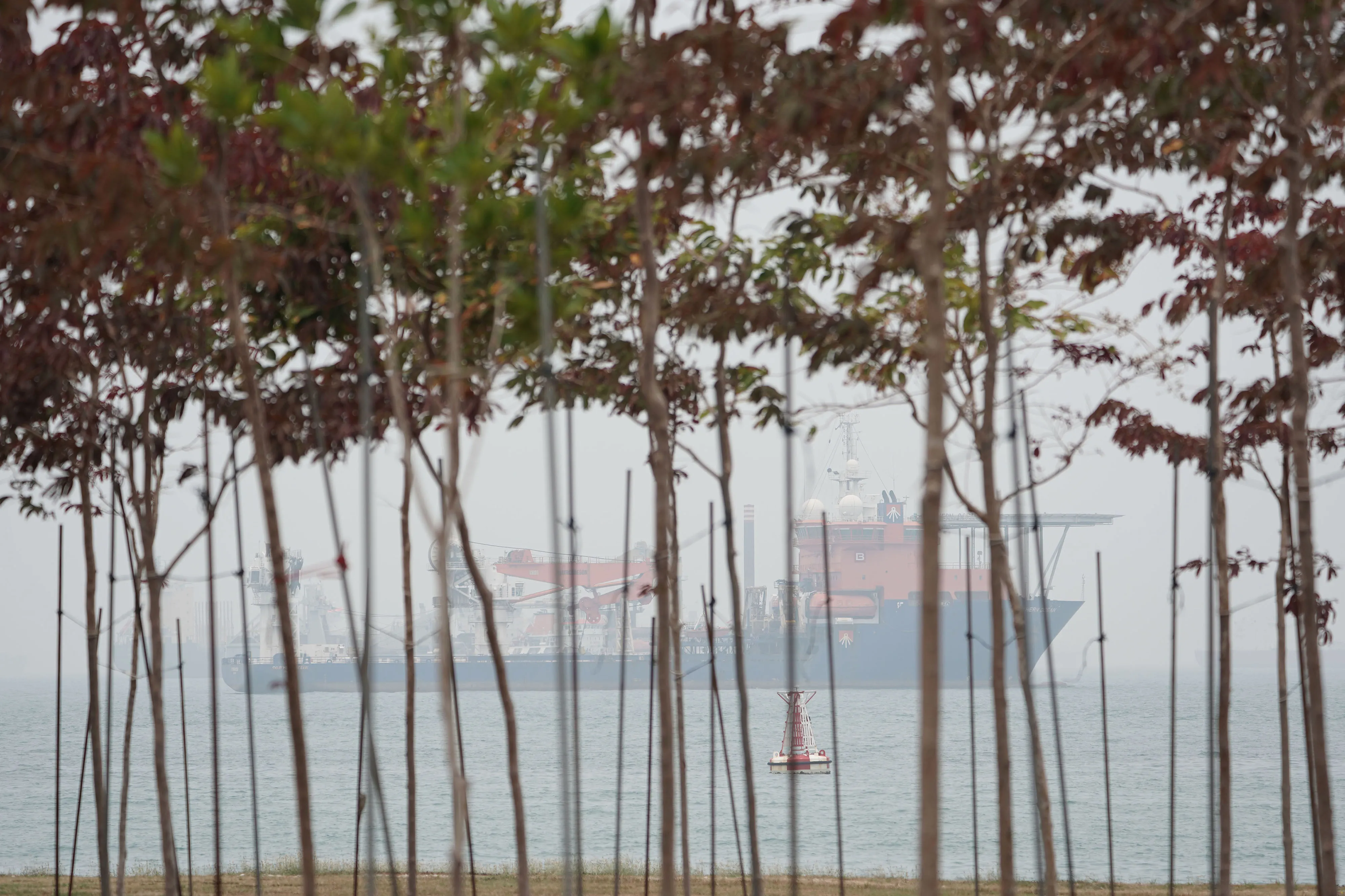 Haze shrouds a cargo ship sailing off the shore of Singapore.