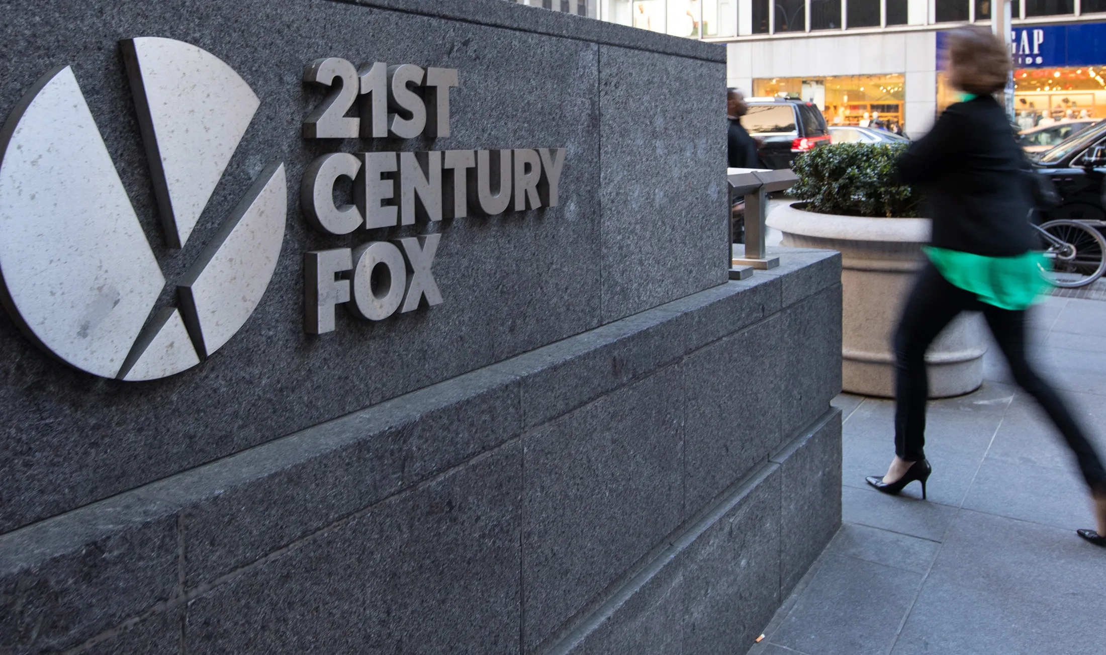 Pedestrians pass in front of signage outside Twenty-First Century Fox Inc. headquarters in New York, on&nbsp;May 3, 2017.