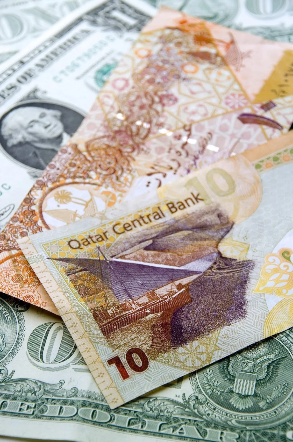 Currency from the Gulf state of Qatar, a Qatari Riyal sits with a U.S. dollar.&nbsp;