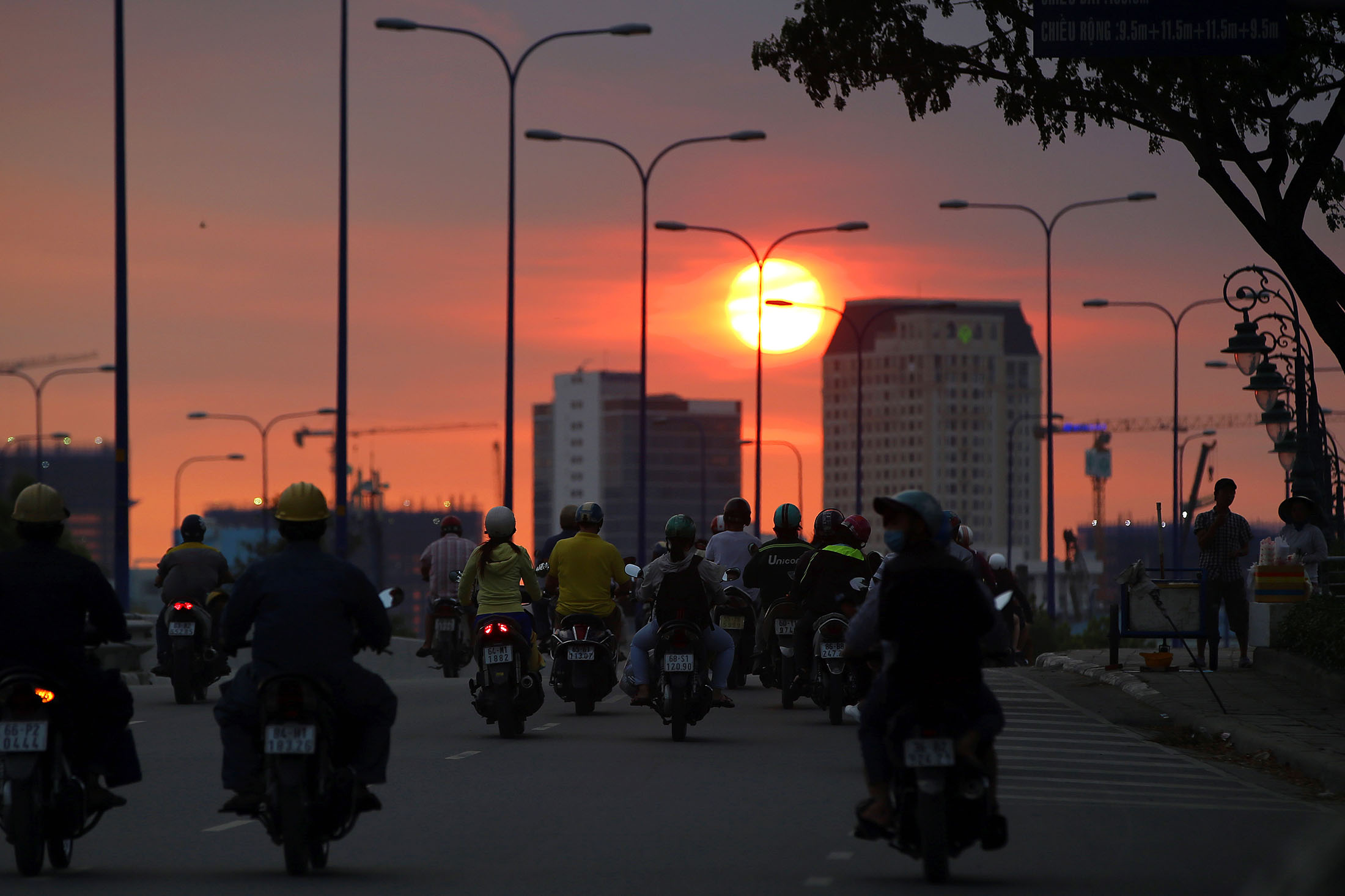 Motorcyclists travel along a road during sunset in Ho Chi Minh City.