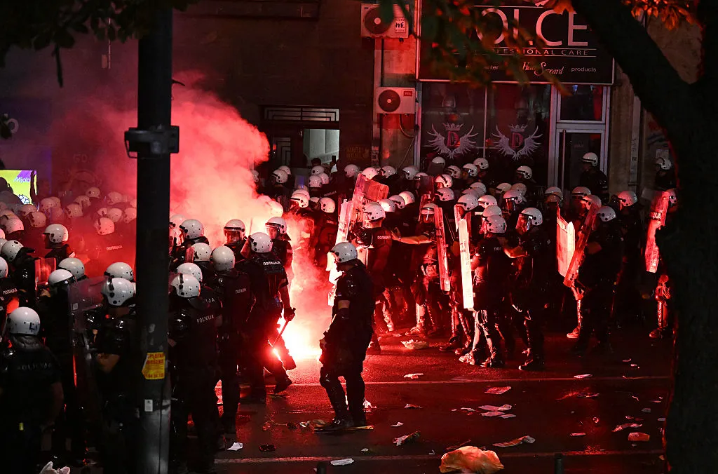 A flare burns as Serbian riot police move towards protesters demanding an early election to oust President&nbsp;Aleksandar Vucic&nbsp;and his governing party&nbsp;in Belgrade on June 28.