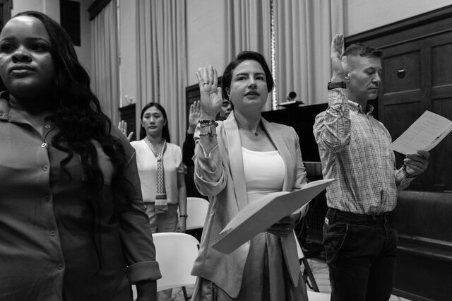 Tatiana Kosareva, middle, and her husband Vladimir Volodin, right, new citizens from Russia, take the Oath of Allegiance during a naturalization ceremony at the US District Court. 