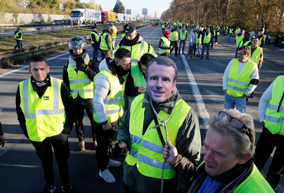 A man wears a mask with the likeness of French president Emmanuel Macron as people take part in the nationwide &quot;Yellow Vest&quot; demonstrations, a symbol of a French drivers' protest against higher fuel prices, in Haulchin, France.