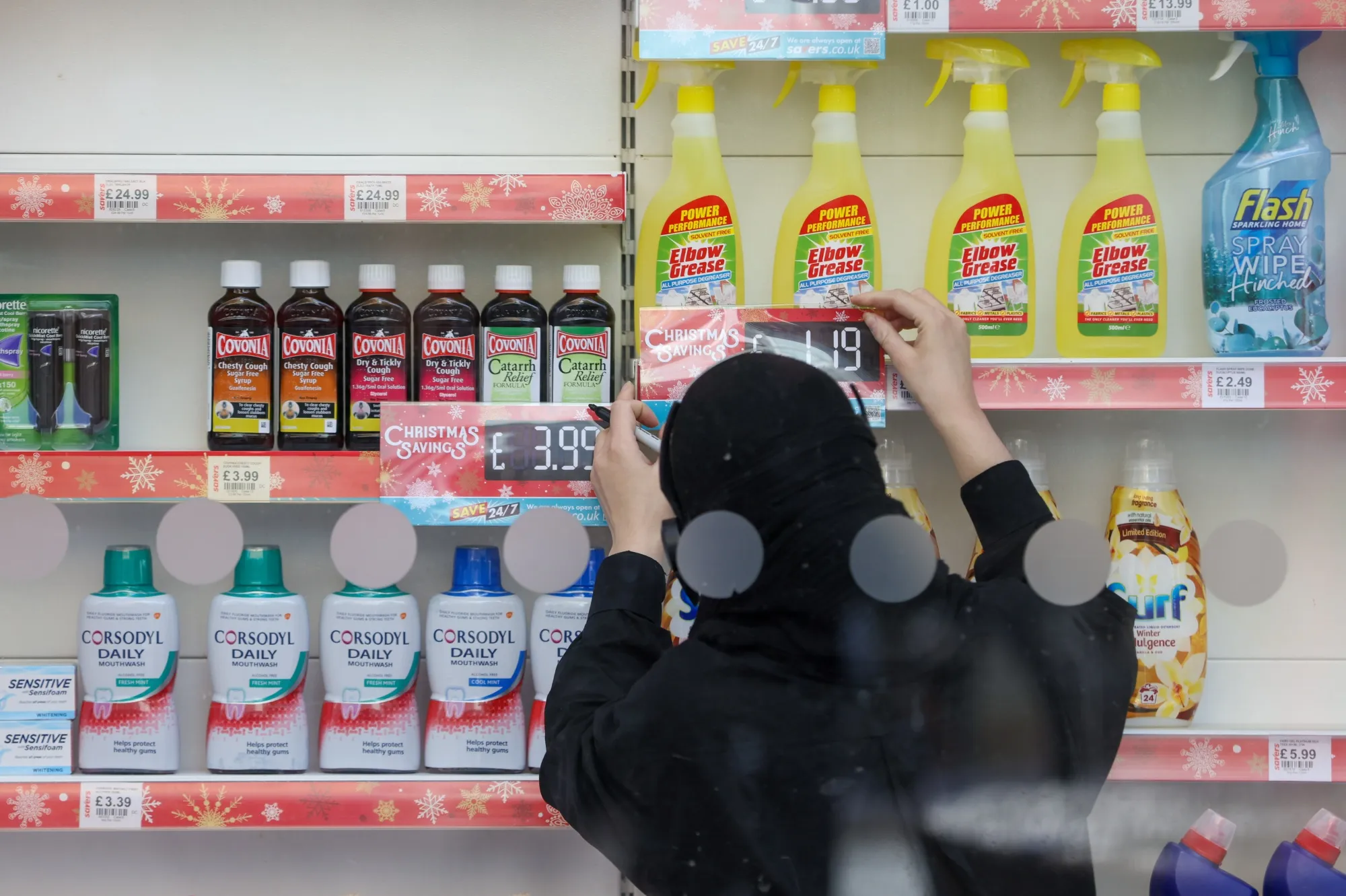 An employee displays Christmas savings prices at a shop in Slough.