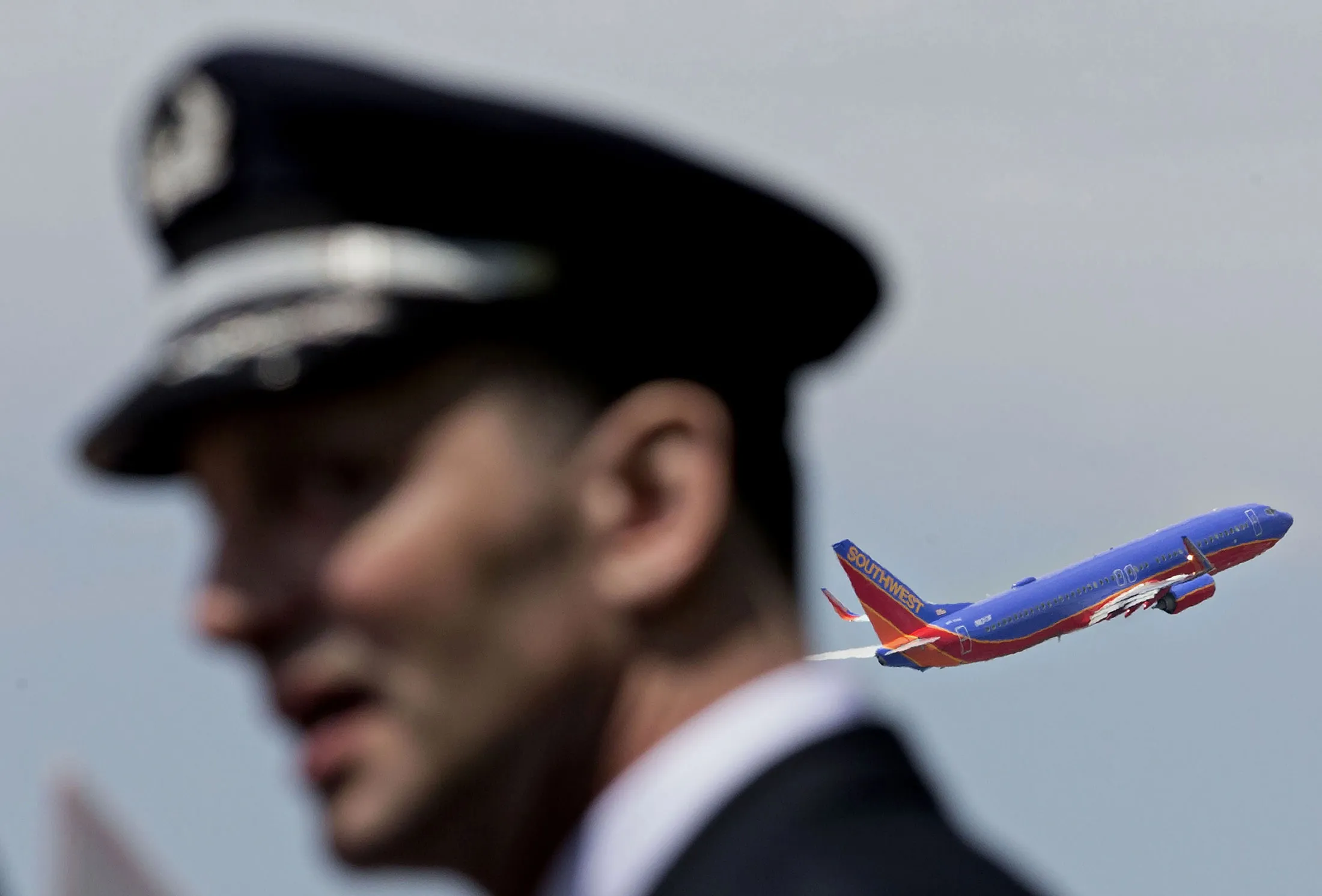 A Southwest Airlines Co. plane takes off a pilot from the Southwest Airlines Pilots' Association (SWAPA) demonstrates outside Chicago Midway International Airport (MDW) in Chicago, Illinois, U.S., on Wednesday, May 18, 2016. Pilots picketed the meeting to protest the lack of a new contract with the company despite four years of negotiations. The union also recently sued the carrier to block it from flying a new aircraft that's not listed in their current contract.
