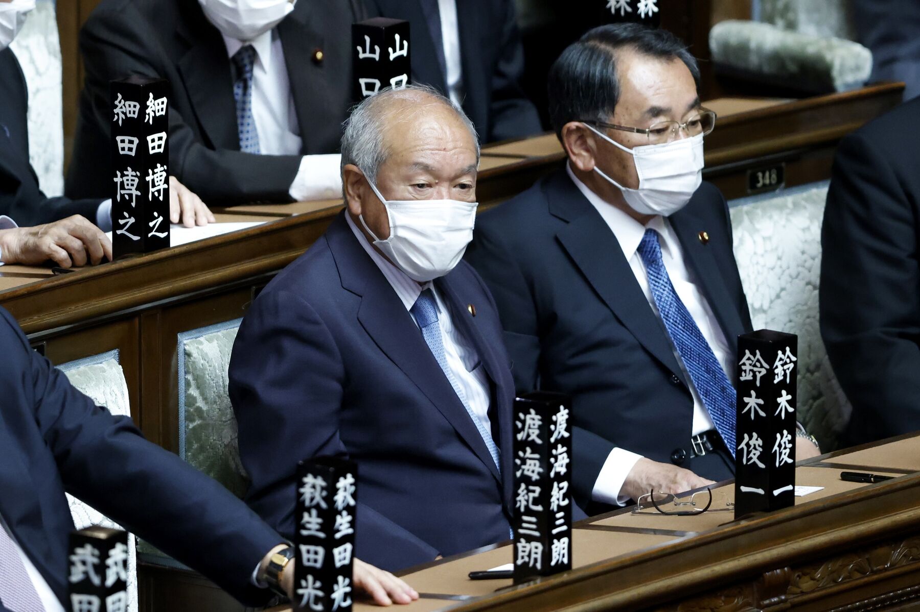 Shunichi Suzuki, Japan's former Olympics and Paralympics minister, left, attends an extraordinary session at the lower house of parliament in Tokyo, Japan, on Monday, Oct. 4, 2021. Fumio Kishida was appointed prime minister by parliament Monday, and is set to reveal a new cabinet lineup as he seeks to revive support for his ruling party ahead of a general election that could likely come this month.
