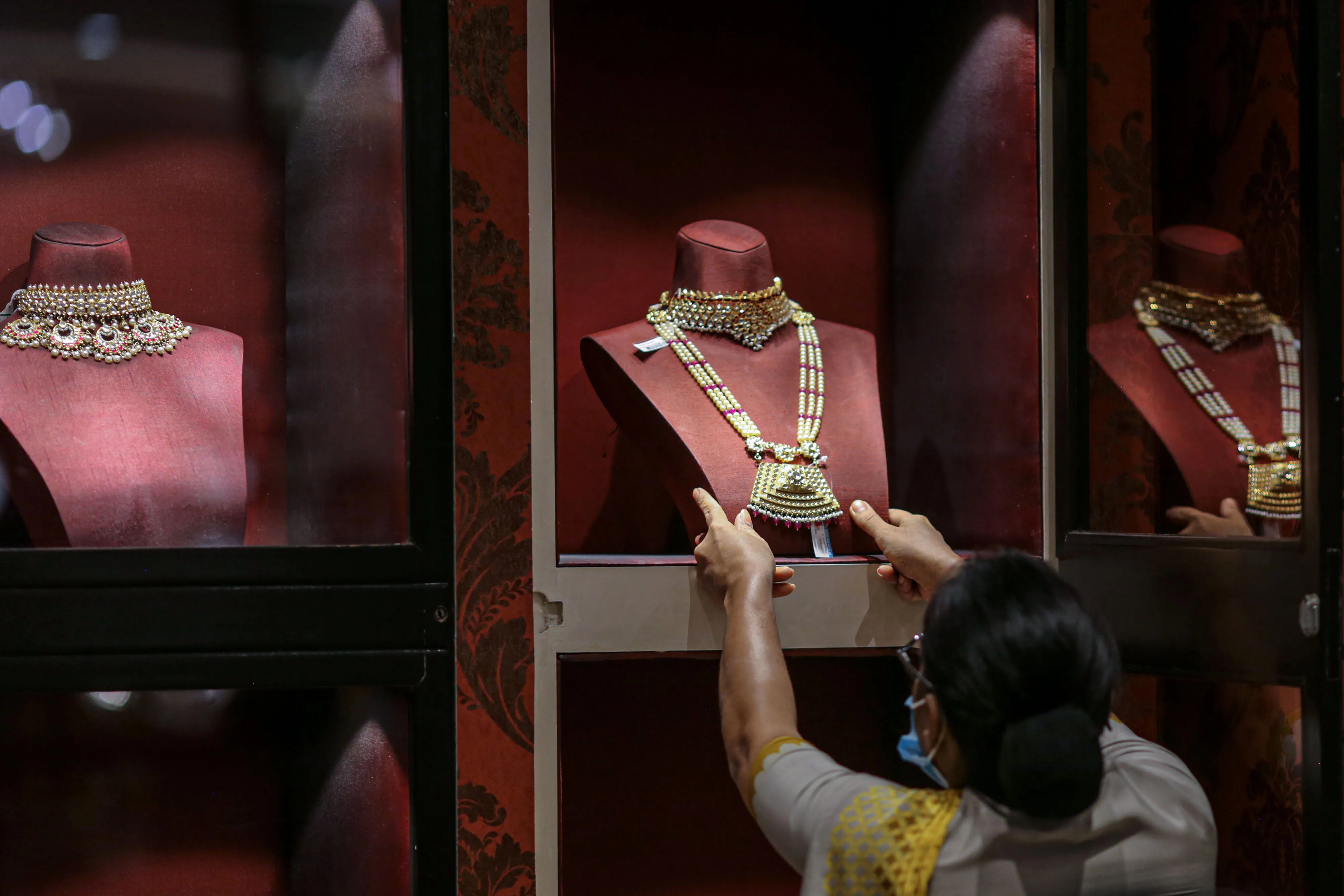 An employee arranges a gold necklace inside a&nbsp;jewelry store in Mumbai.