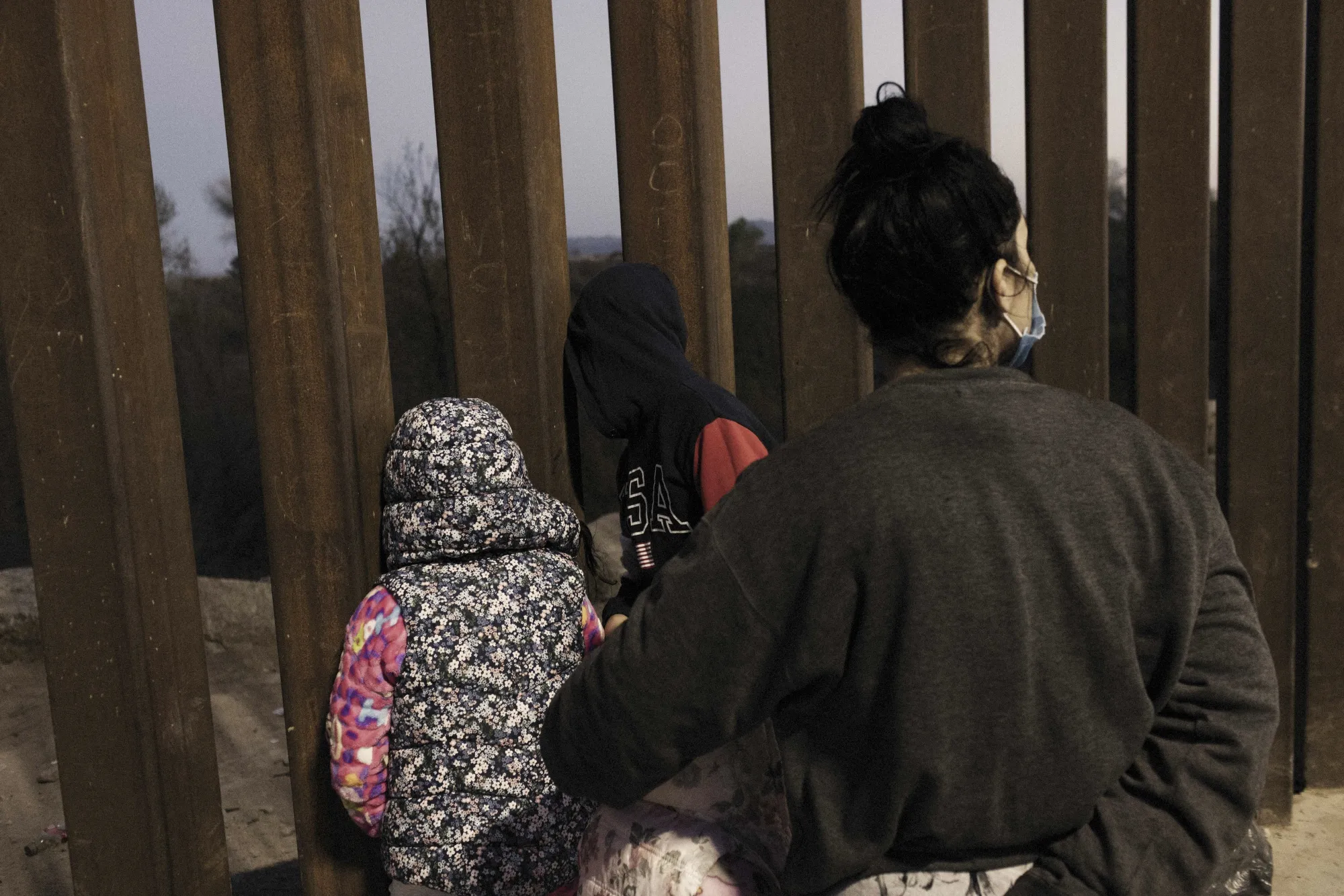 Migrant children seeking asylum look through a section of the U.S. and Mexico border fence in Yuma, Arizona,&nbsp;on&nbsp;Feb. 17.&nbsp;