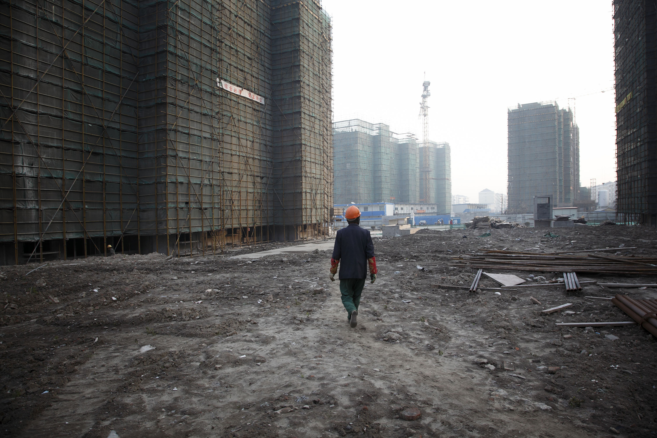A worker walks through the grounds of an unfinished apartment complex in Shanghai.