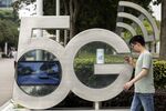 An employee using a smartphone walks past a sign for the 5G Park at the Huawei Technologies Co. headquarters in Shenzhen, China.