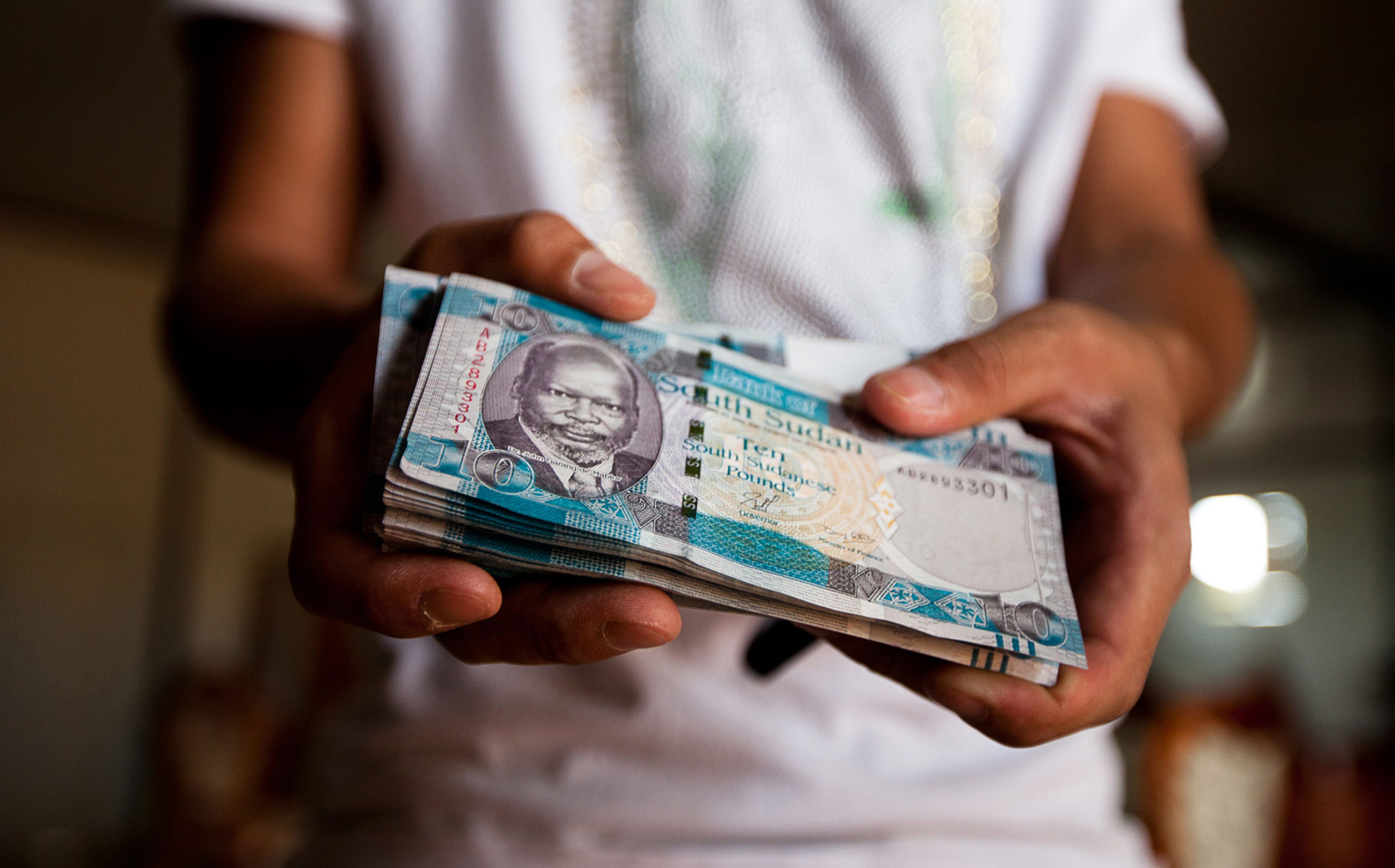 A man holds a stack of ten South Sudanese pound banknotes in South Sudan.
