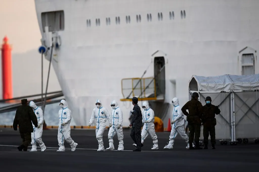 People wearing protective suits walk from the Diamond Princess cruise ship, with around 3,600 people quarantined onboard due to fears of the new coronavirus, at the Daikoku Pier Cruise Terminal in Yokohama port.&nbsp;