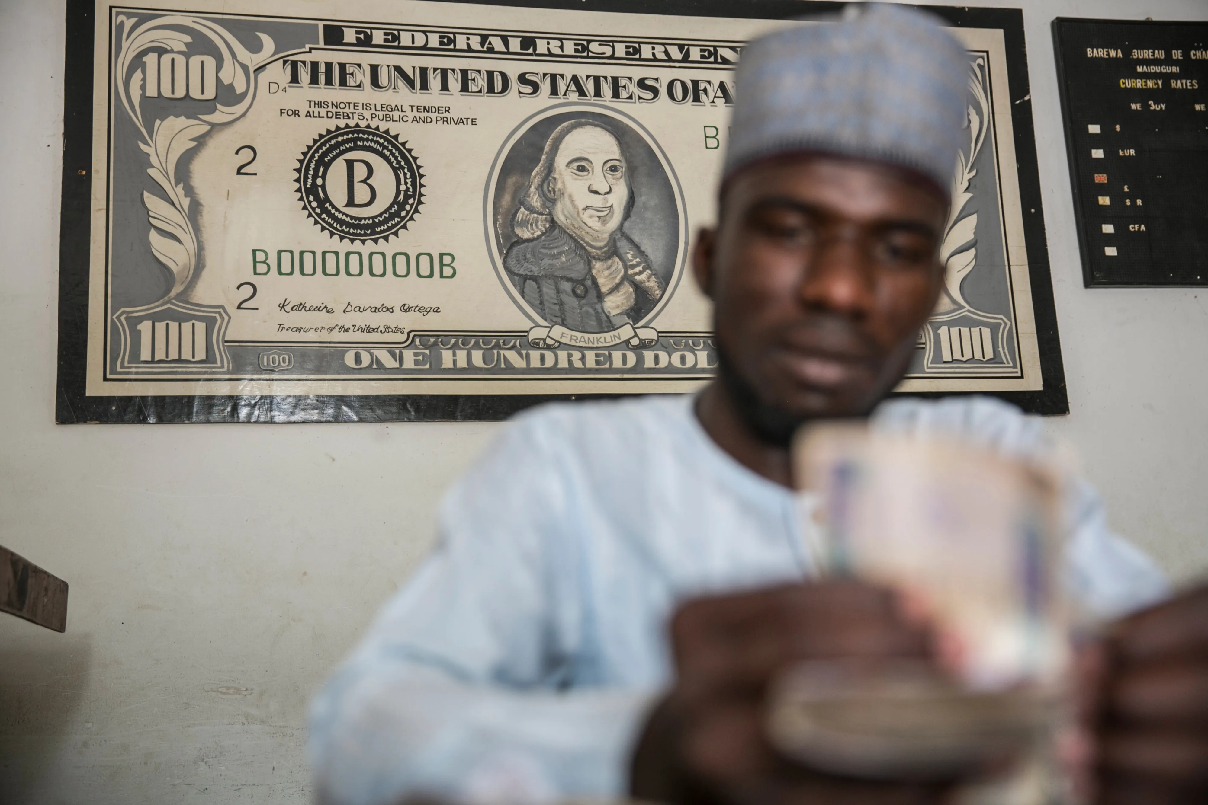 A currency exchange clerk counts naira banknotes in Maiduguri, Nigeria.